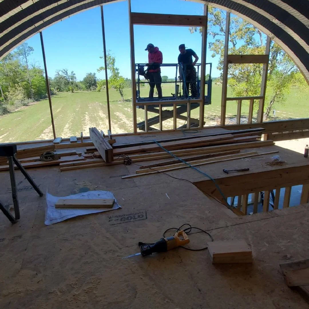 Interior view of a custom arched building under construction with Tindall Construction crew installing window framing using a lift.