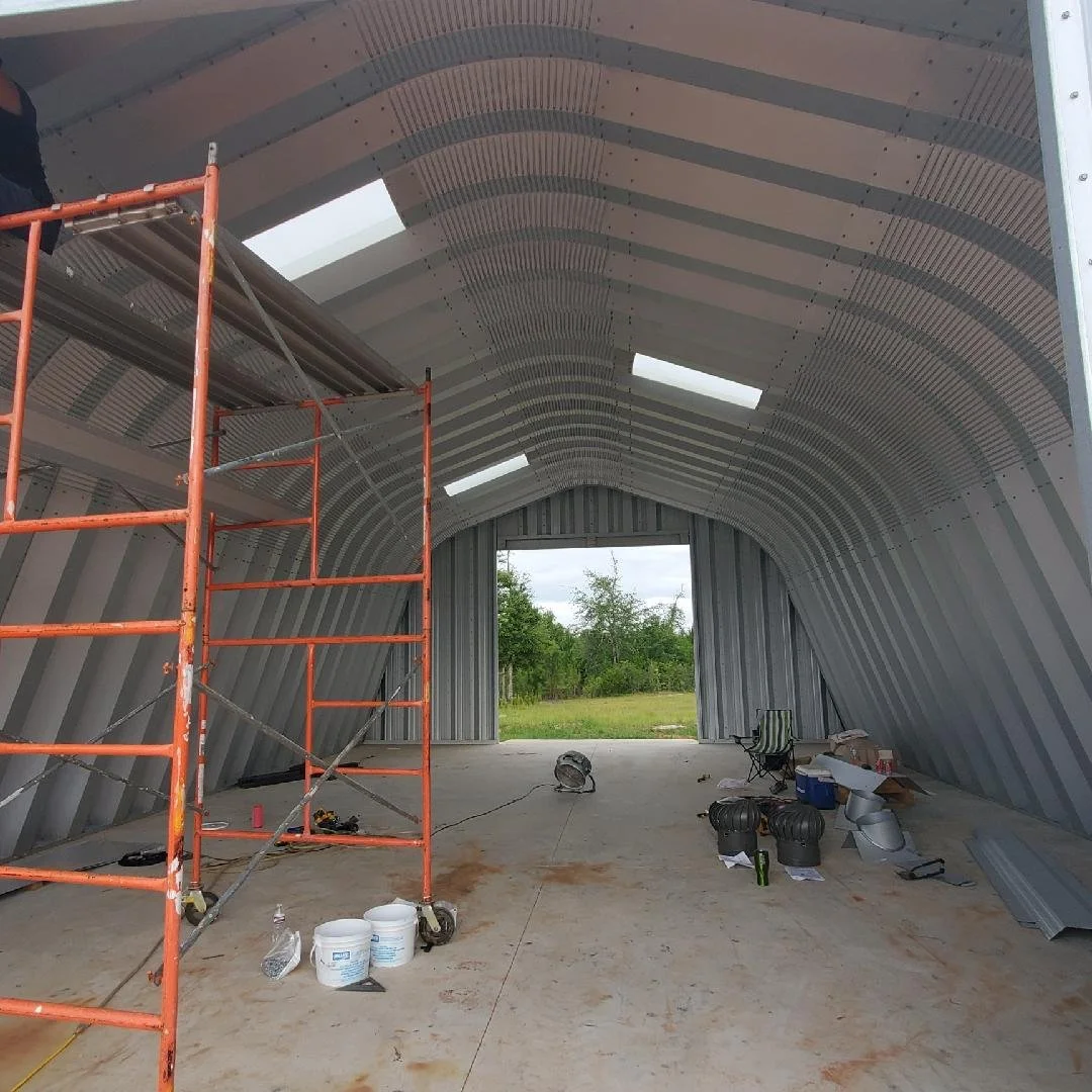 Interior of a curved metal building under construction showing structural framing and materials installed by Tindall Construction.