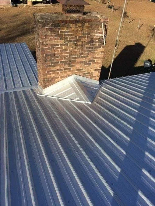 Metal roof installation featuring chimney and skylight penetration completed during construction by Tindall Construction.