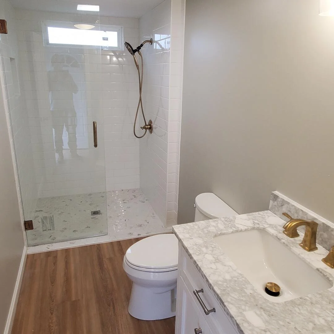 Finished bathroom renovation featuring a glass-enclosed shower, marble vanity, and upgraded fixtures completed by Tindall Construction.