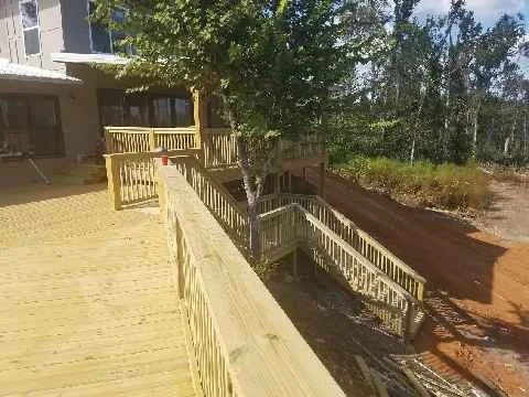 Residential wooden deck with stairs providing yard access, constructed by Tindall Construction.