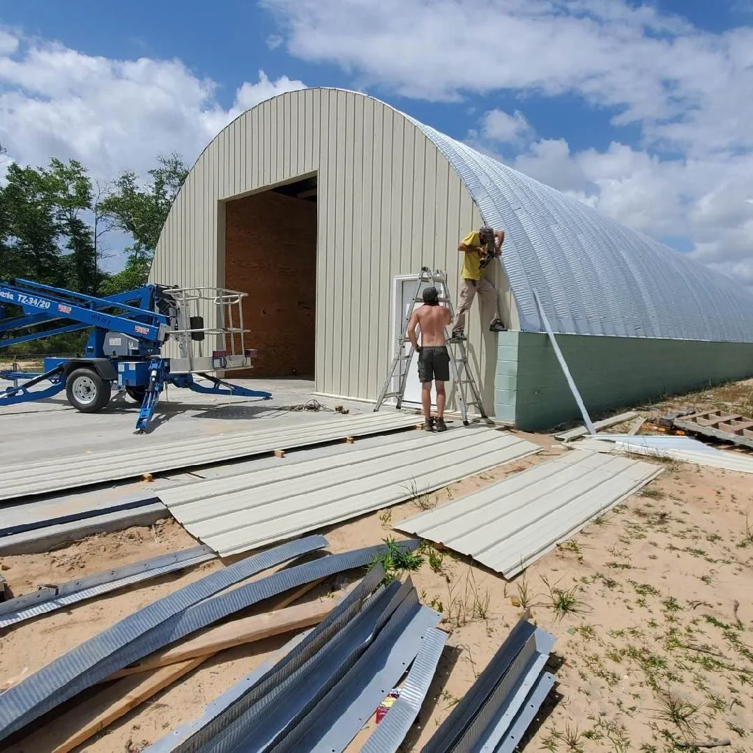 Tindall Construction crew installing metal building panels during active construction, with materials staged on site.