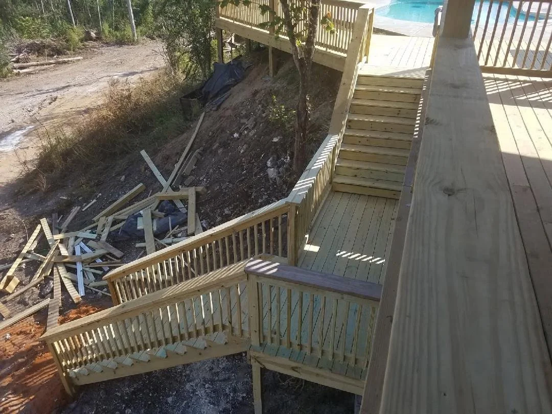 Custom wooden deck with stairs constructed by Tindall Construction, overlooking a residential pool area.