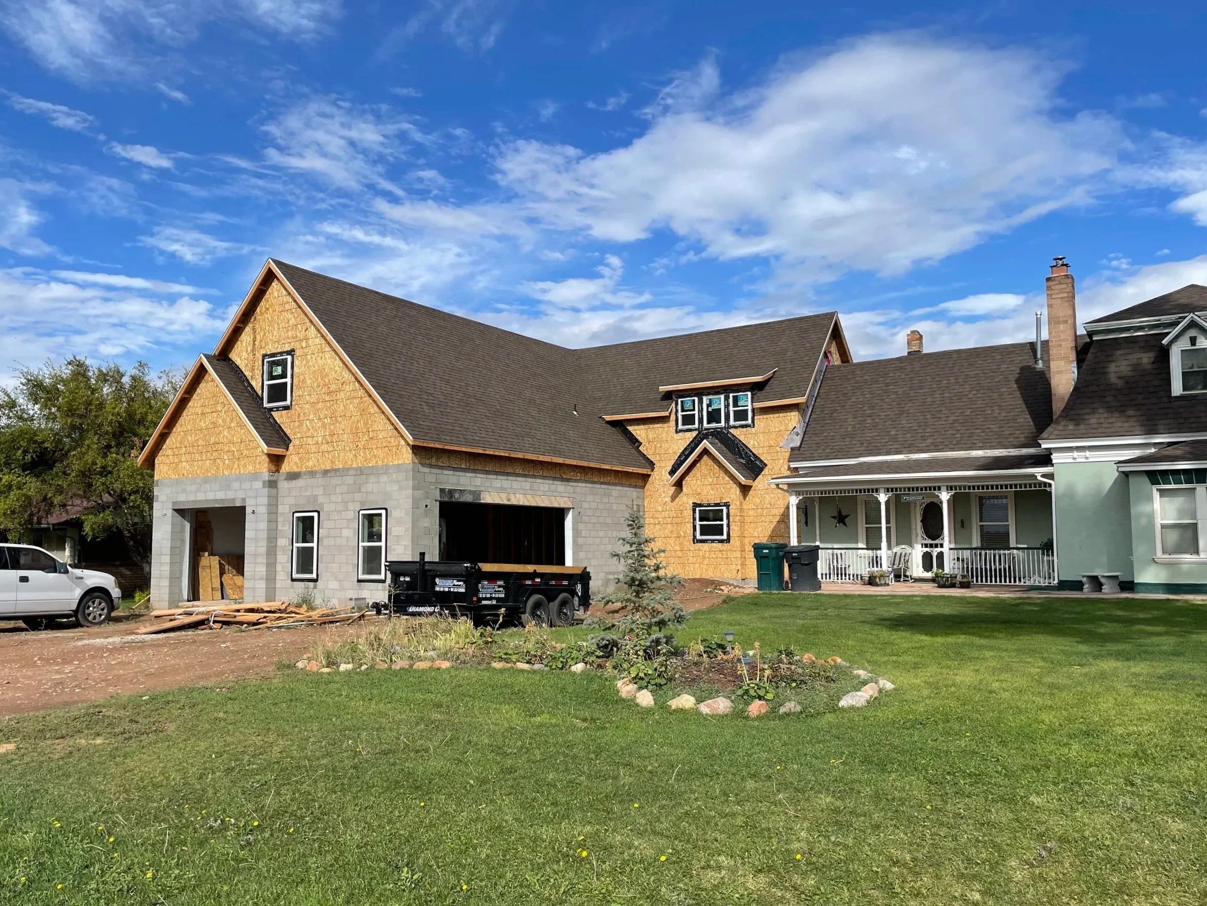 Modern kitchen with a large gray island, black cabinetry, and large windows overlooking trees.
