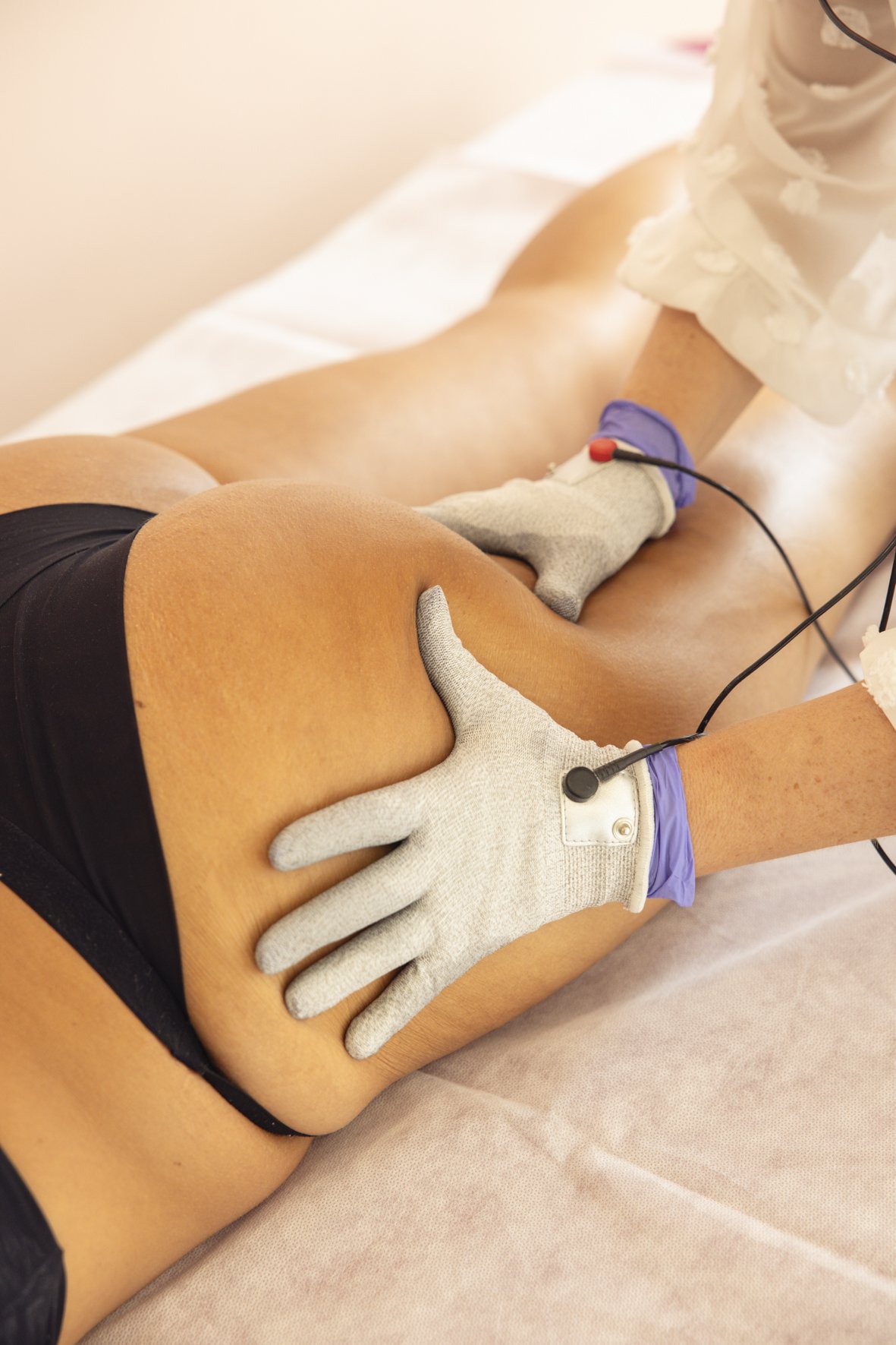 Une femme reçoit une séance de Manutech®, micro-courants et thérapie manuelle au niveau des fesses et de la cuisse. Svenja DELACOUR ISLER accompagneme à la perte de poids et au raffermissement post partum.