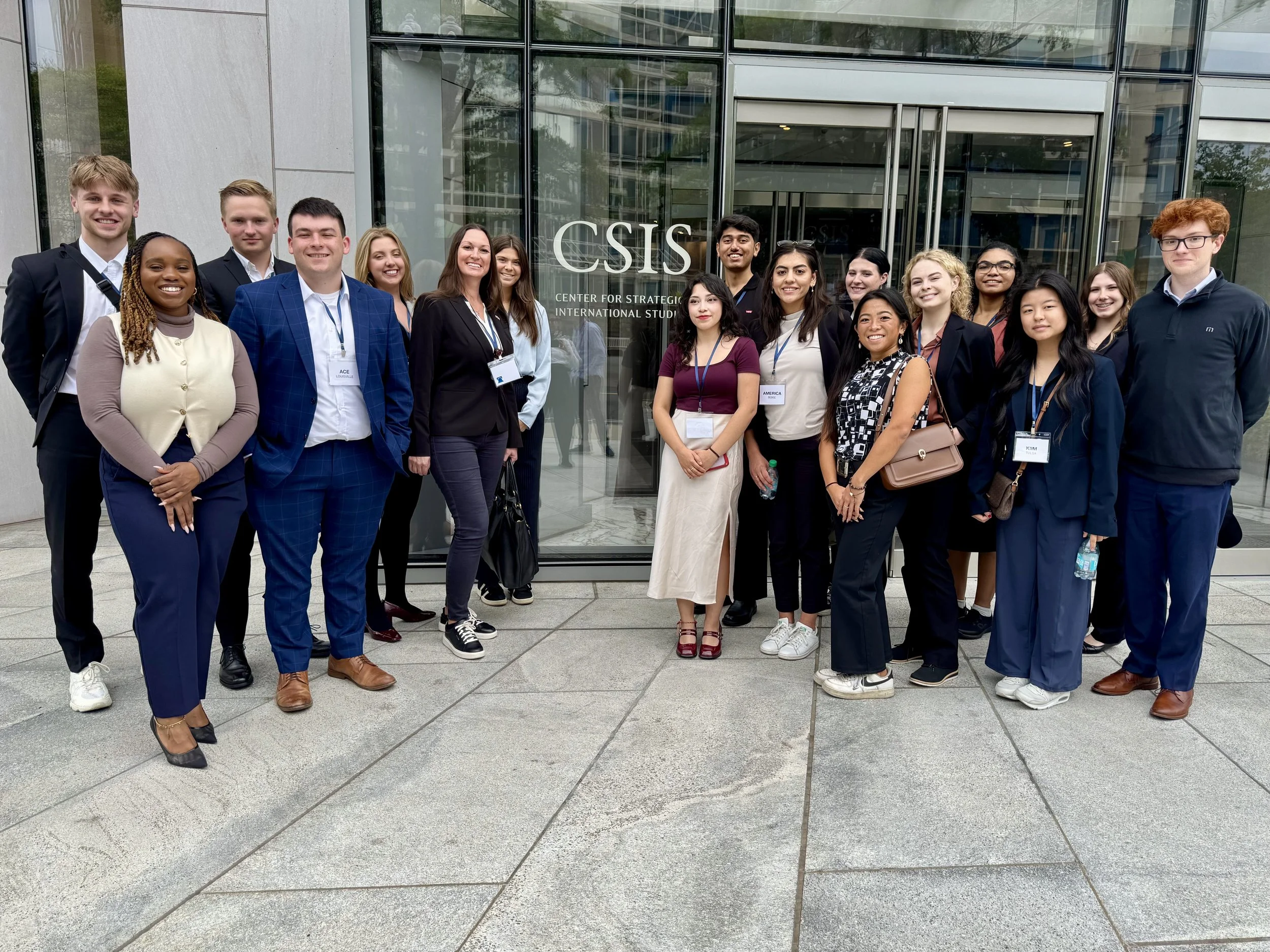 Group of young people standing behind a podium with the U.S. Department of State seal, in a formal setting.