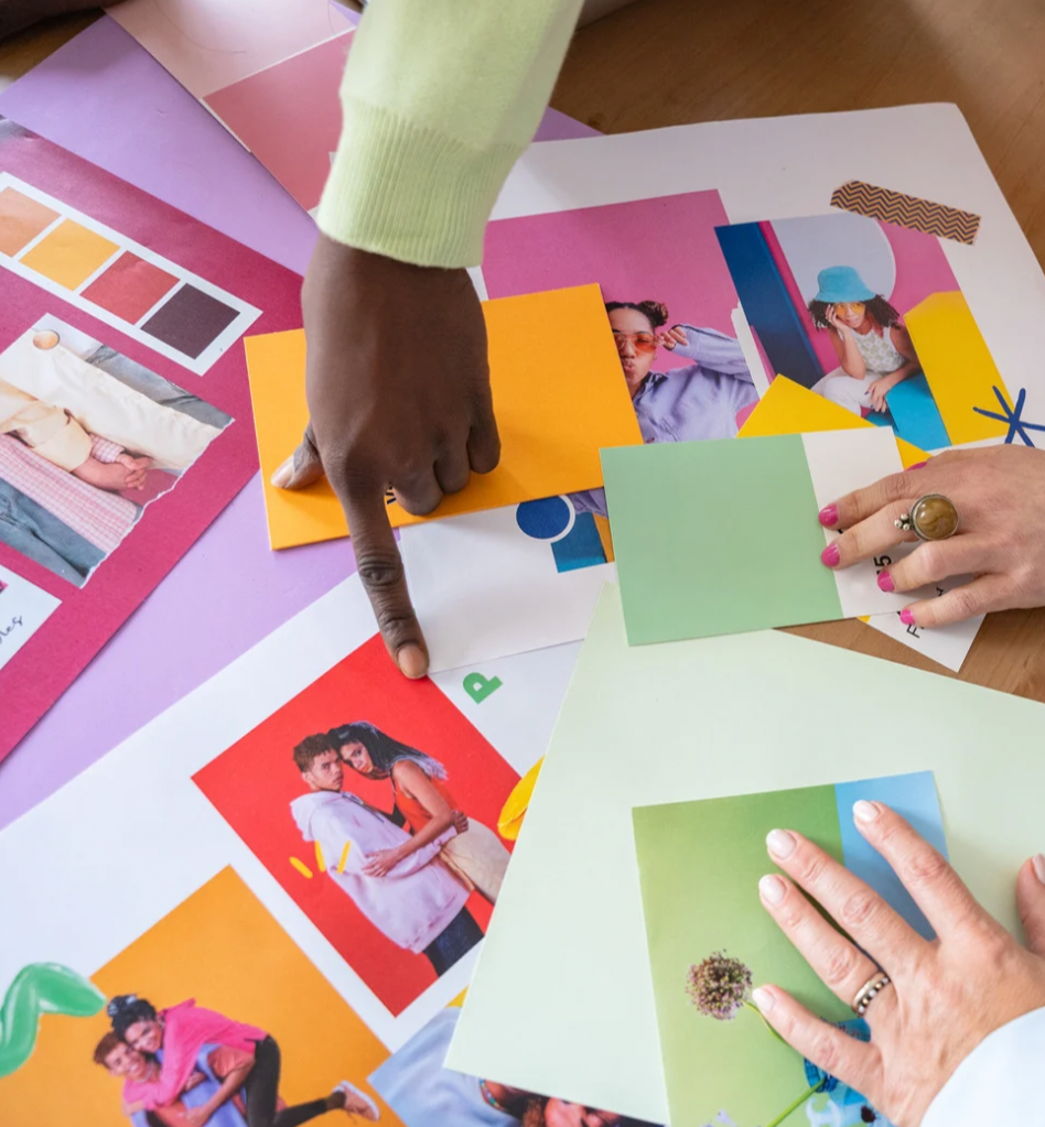People working on a collage with colorful papers and photographs, including images of young adults, with painter's tape on the sides. Creative interventions for therapy clients who want to reconnect with their identity and intuition.