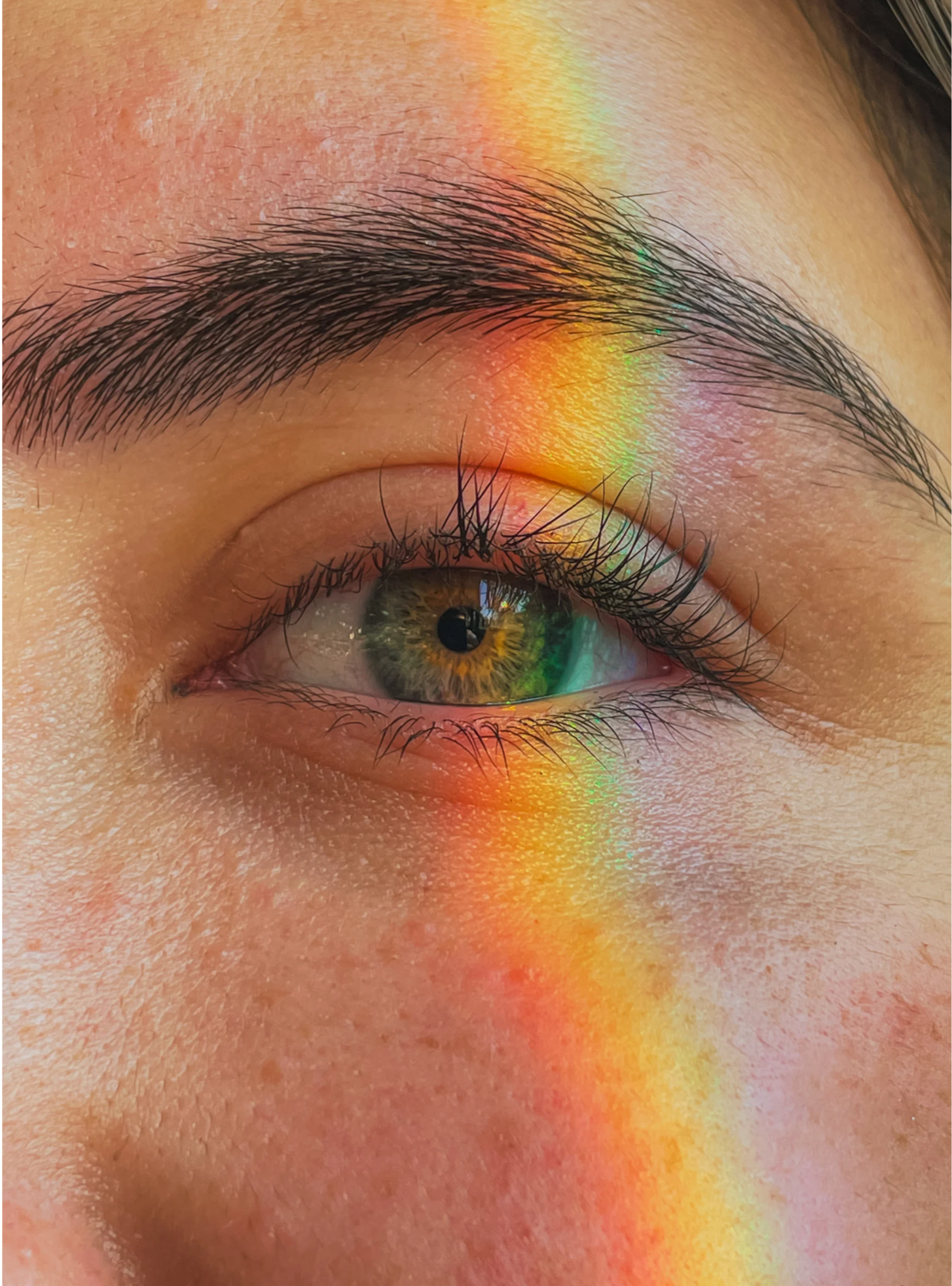 Close-up of a human eye with a rainbow reflection across the eyelid and skin surrounding the eye. Eye movement desensitization and reprocessing therapy interventions.