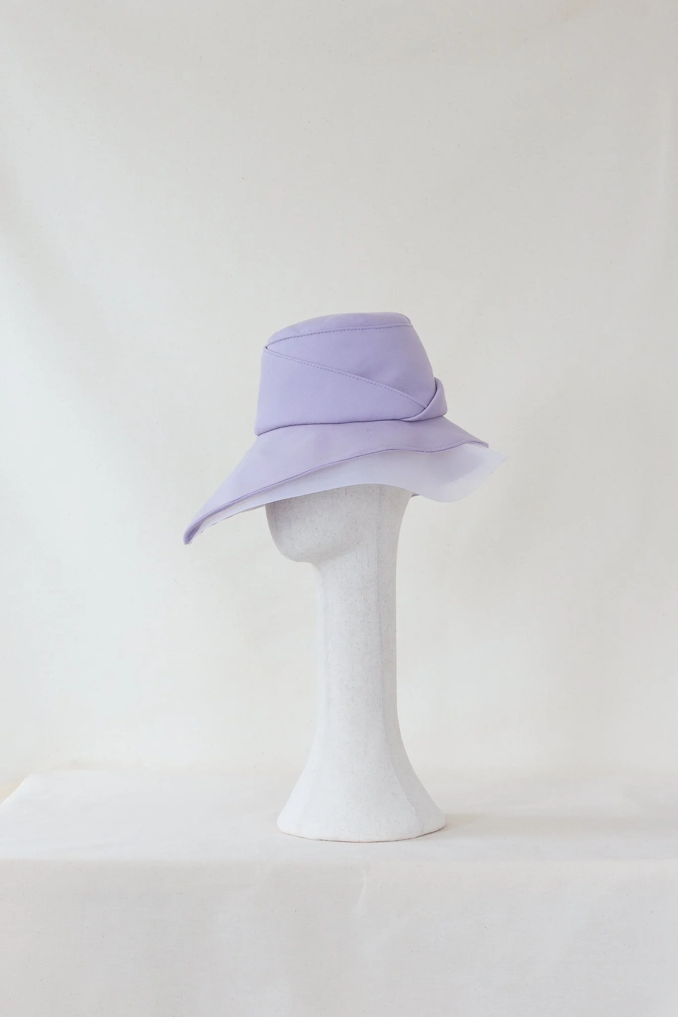 A lavender-colored wide-brimmed hat displayed on a white mannequin head against a plain white background.