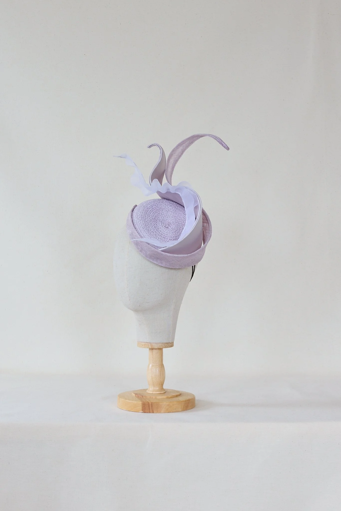 A handmade paper sculpture of a swan with a flowing neck and wings, mounted on a wooden stand, set against a neutral background.