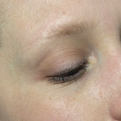 Close-up of a person's face showing closed eye with light skin and minimal makeup.