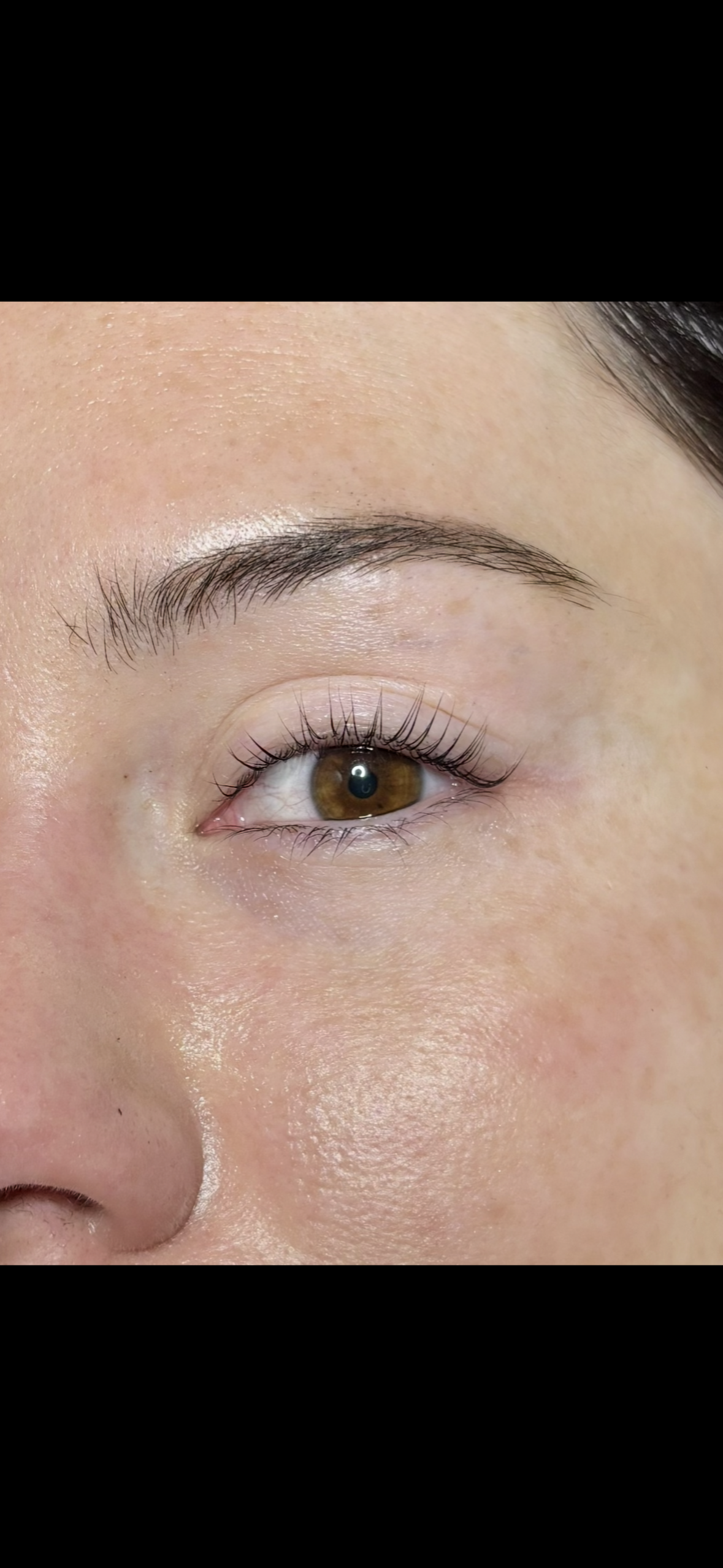 Close-up of a person's eye with brown iris, natural eyebrows, and visible eyelashes.