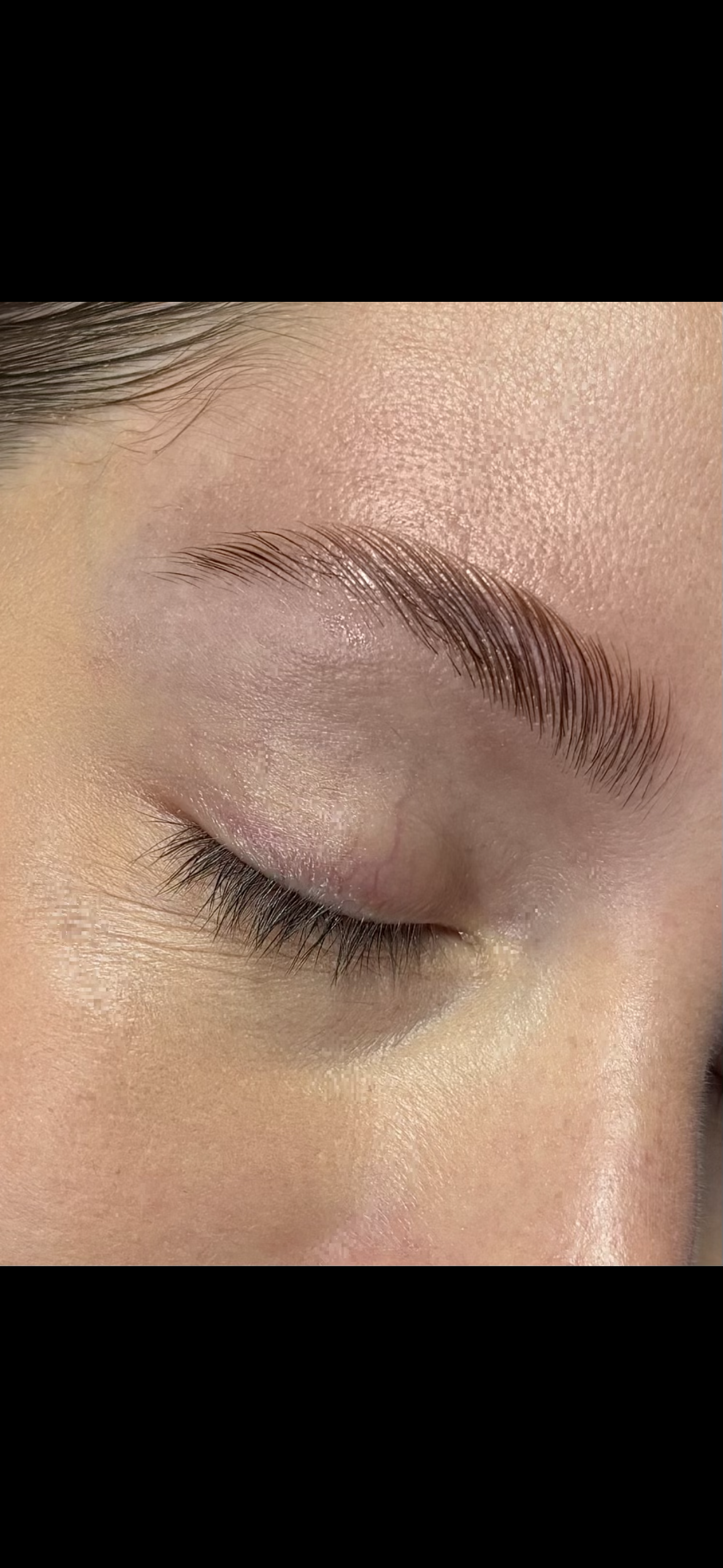 Close-up of a person's closed eye showcasing smooth skin, natural eyebrow, and long eyelashes.