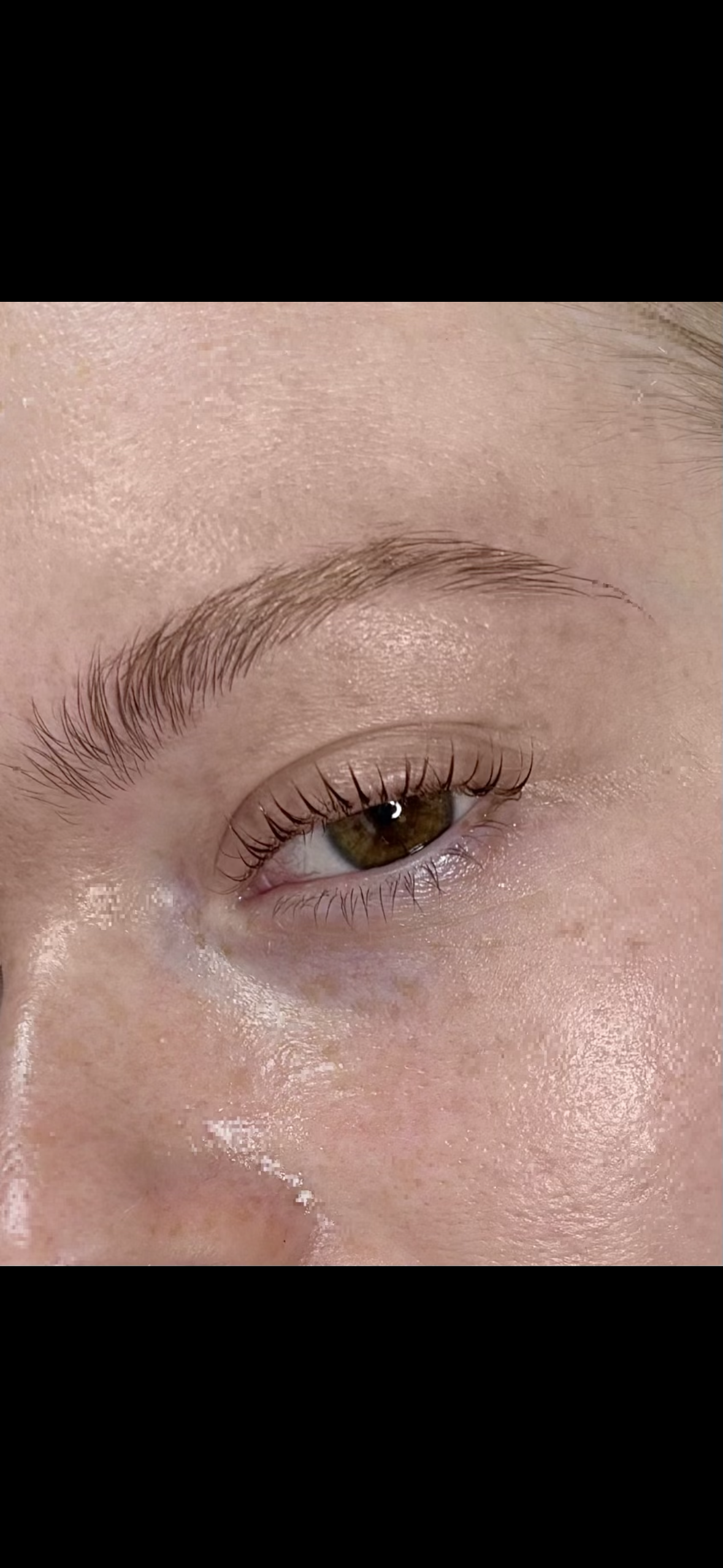 Close-up of a person's eye showing brown iris, long lashes, well-groomed eyebrow, and smooth skin.