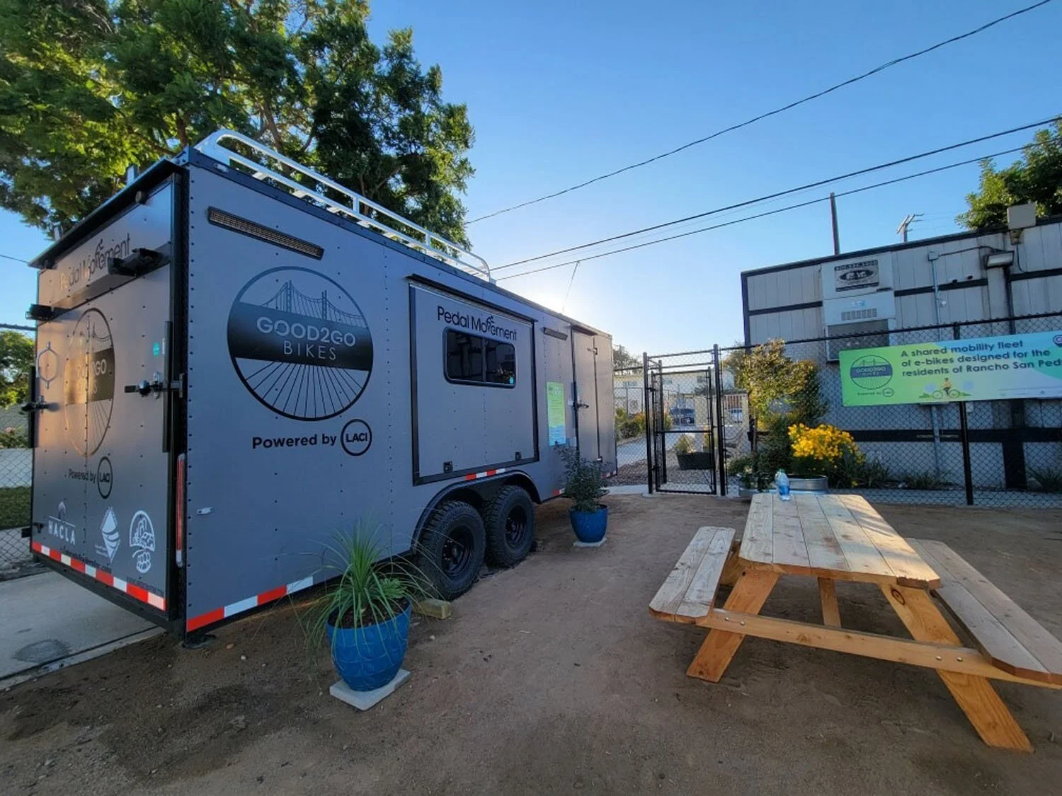 Grey trailer with Pedal Movement and Good2Go Bikes branding with a picnic table