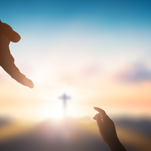 Silhouettes of two hands reaching towards a cross at sunrise or sunset with a blurred sky background.