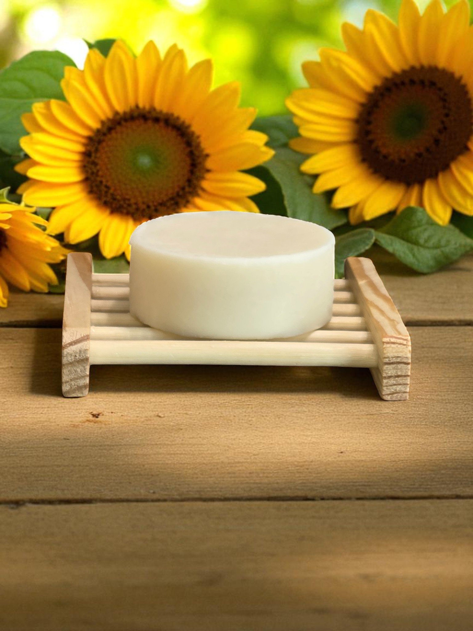 A metal tin of foot balm labeled 'Watermelon Sugar' with a pink and green watermelon-themed label, placed on a white surface beside a pink towel, near a window.