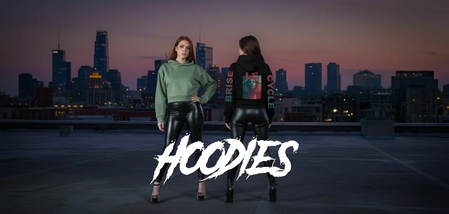 Deux femmes portant des sweat-shirts en cuir sur un toit avec une skyline de ville en arrière-plan, au crépuscule. La femme de gauche porte un sweat vert et la femme de droite un sweat noir avec des écritures en couleur.