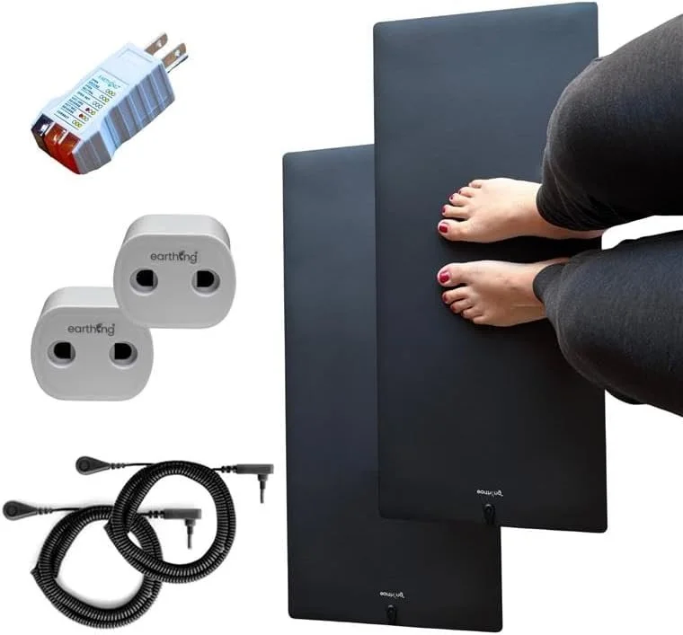 A person doing a fitness or yoga pose on two black exercise mats, with two electrical outlets, a power cord, a power strip, and an extension cord also visible.