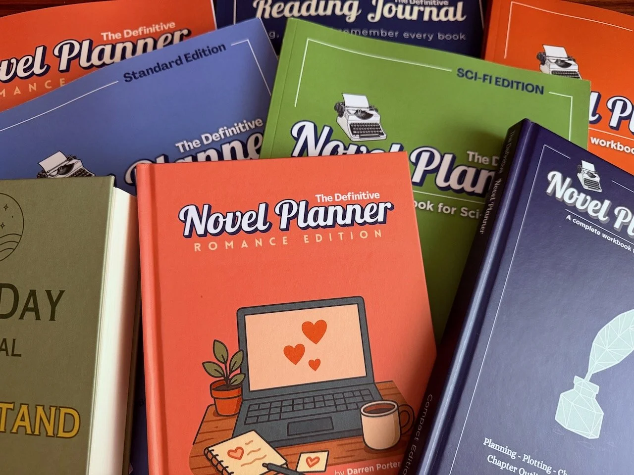 Multiple colorful notebooks and planners stacked on top of each other, including a red romance edition, a blue standard edition, a green sci-fi edition, and a dark blue complete workbook, all titled "Novel Planner" with illustrations of typewriters and related graphics.