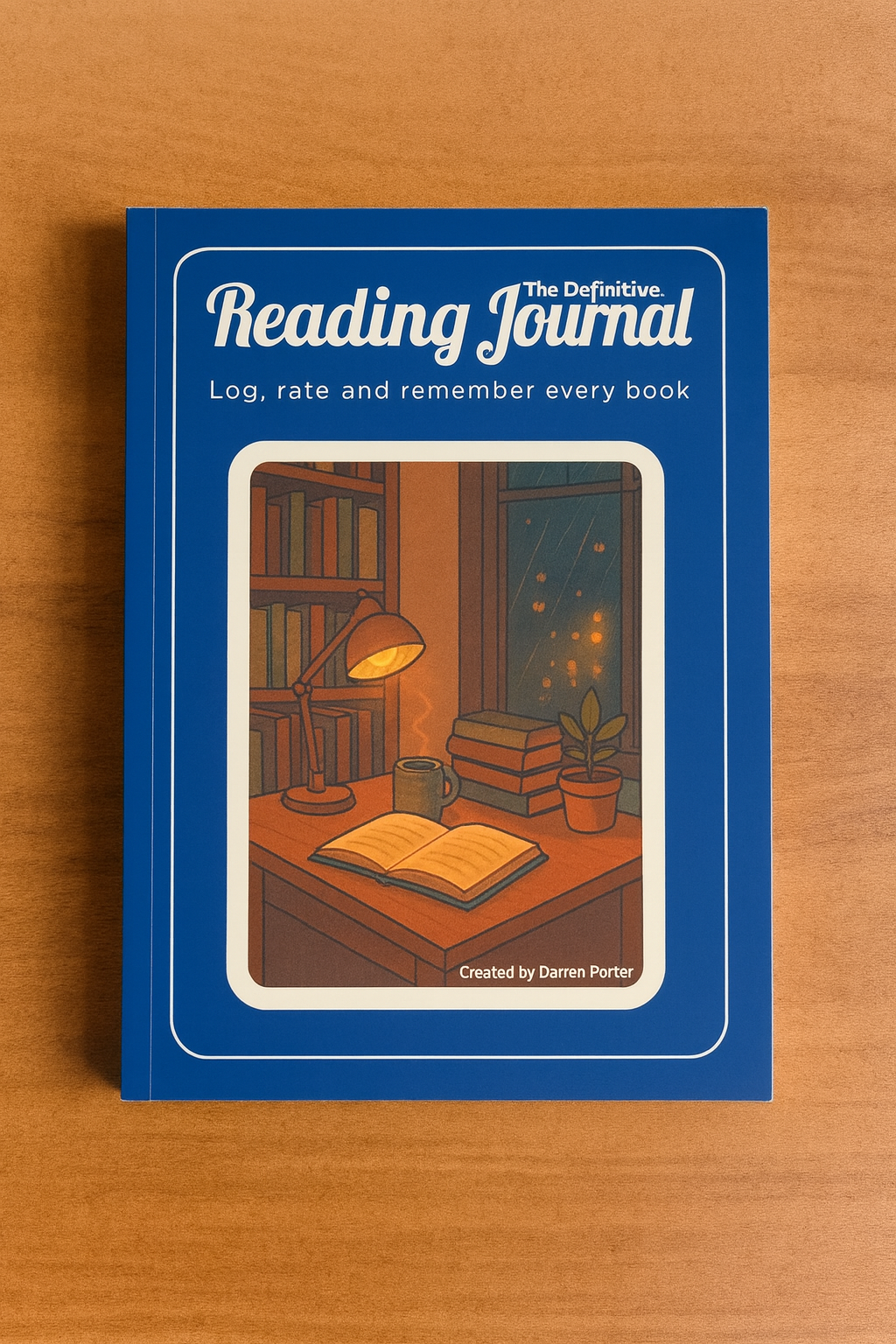 A blue hardcover reading journal with an illustration of a cozy reading nook on the cover, including a desk lamp, books, a potted plant, and a window with rain outside.