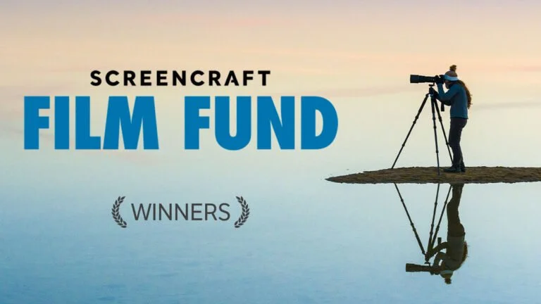 A person using a camera on a tripod standing on a small piece of land by a body of water, with a sunset or sunrise in the background, promoting the Screencraft Film Fund for winners.