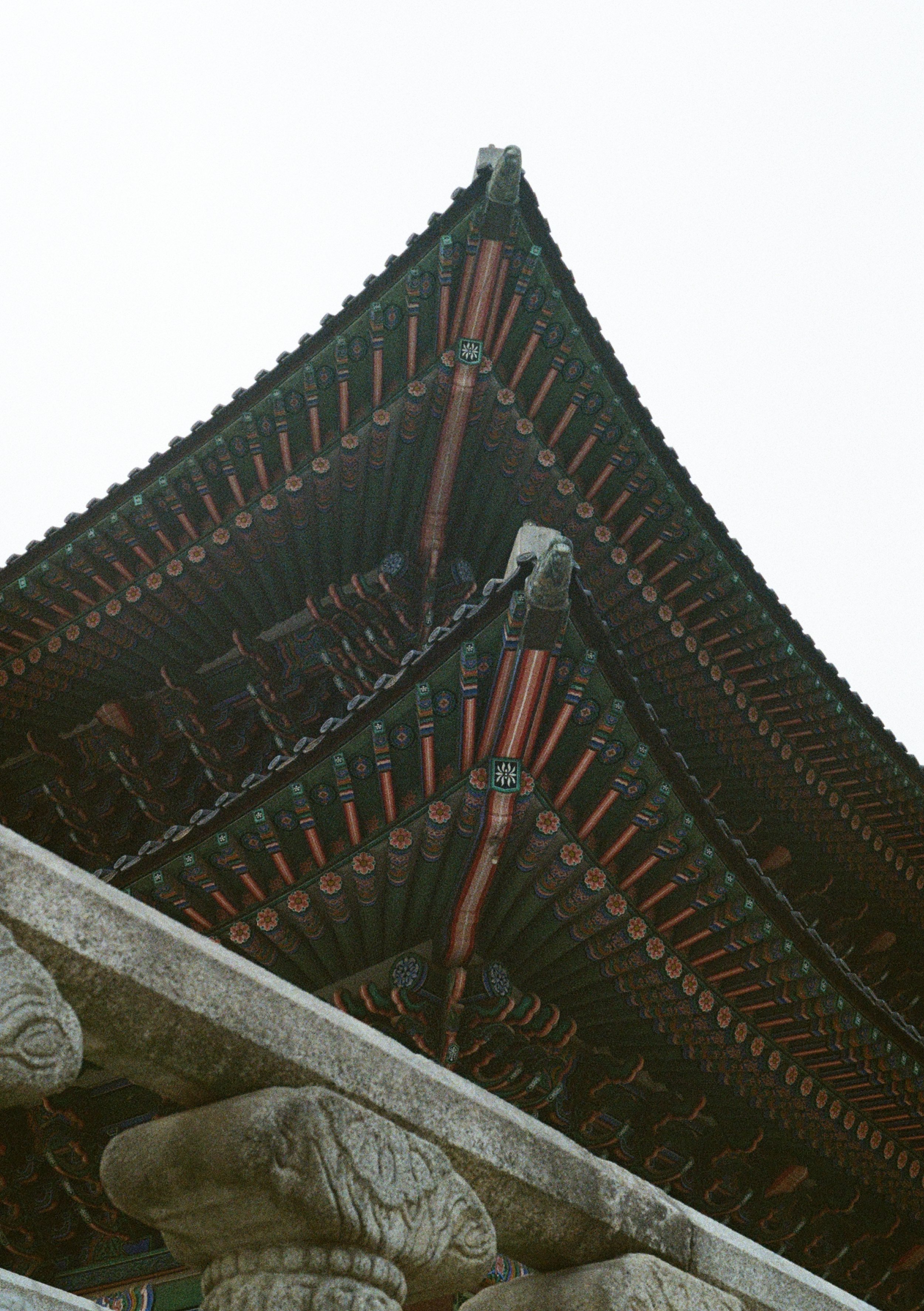 Close-up of the ornate, colorful wooden eaves of a traditional Asian temple roof, showcasing detailed patterns and carvings.