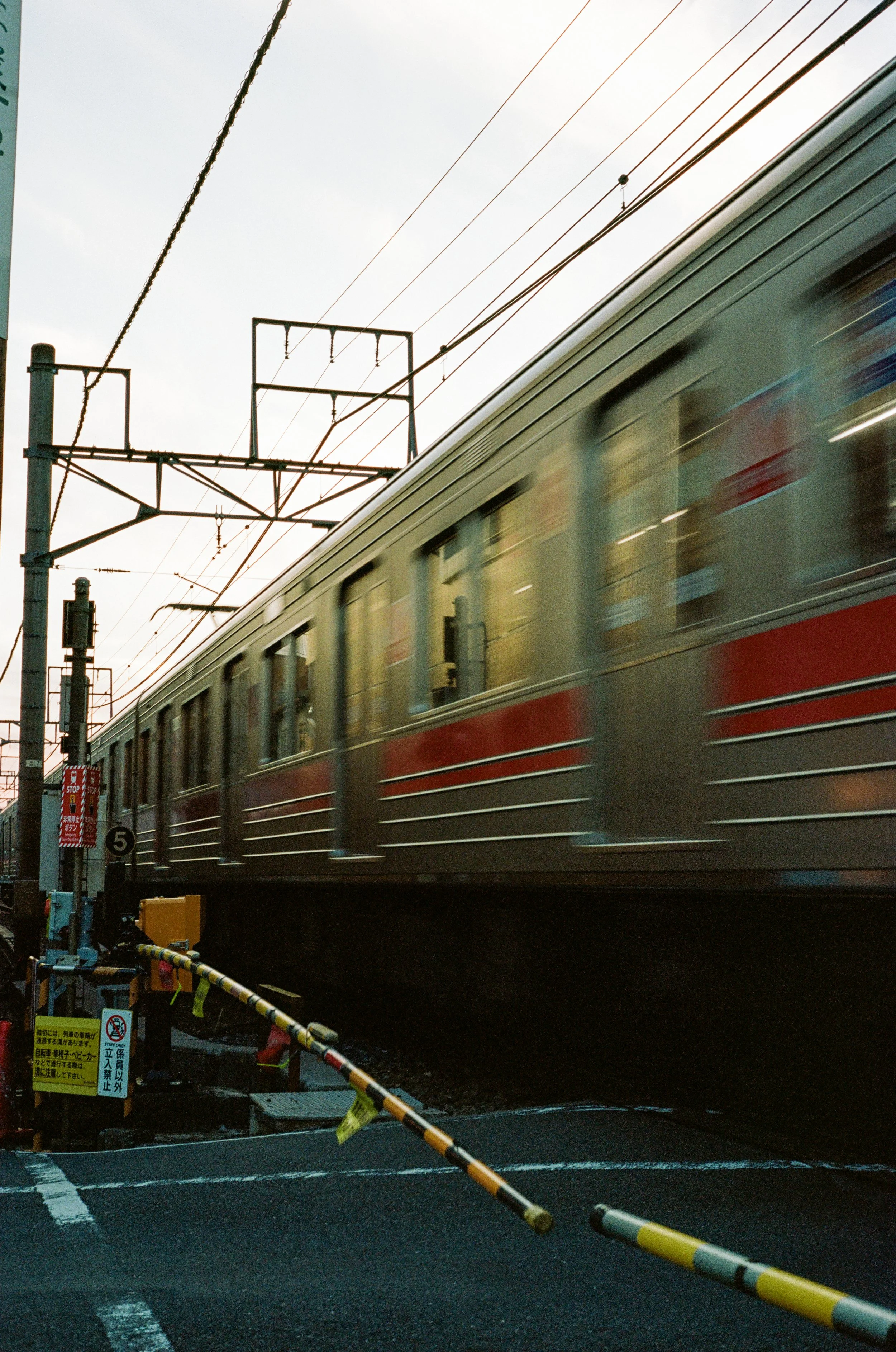 A train passing over a crossing with warning signals and a barrier.
