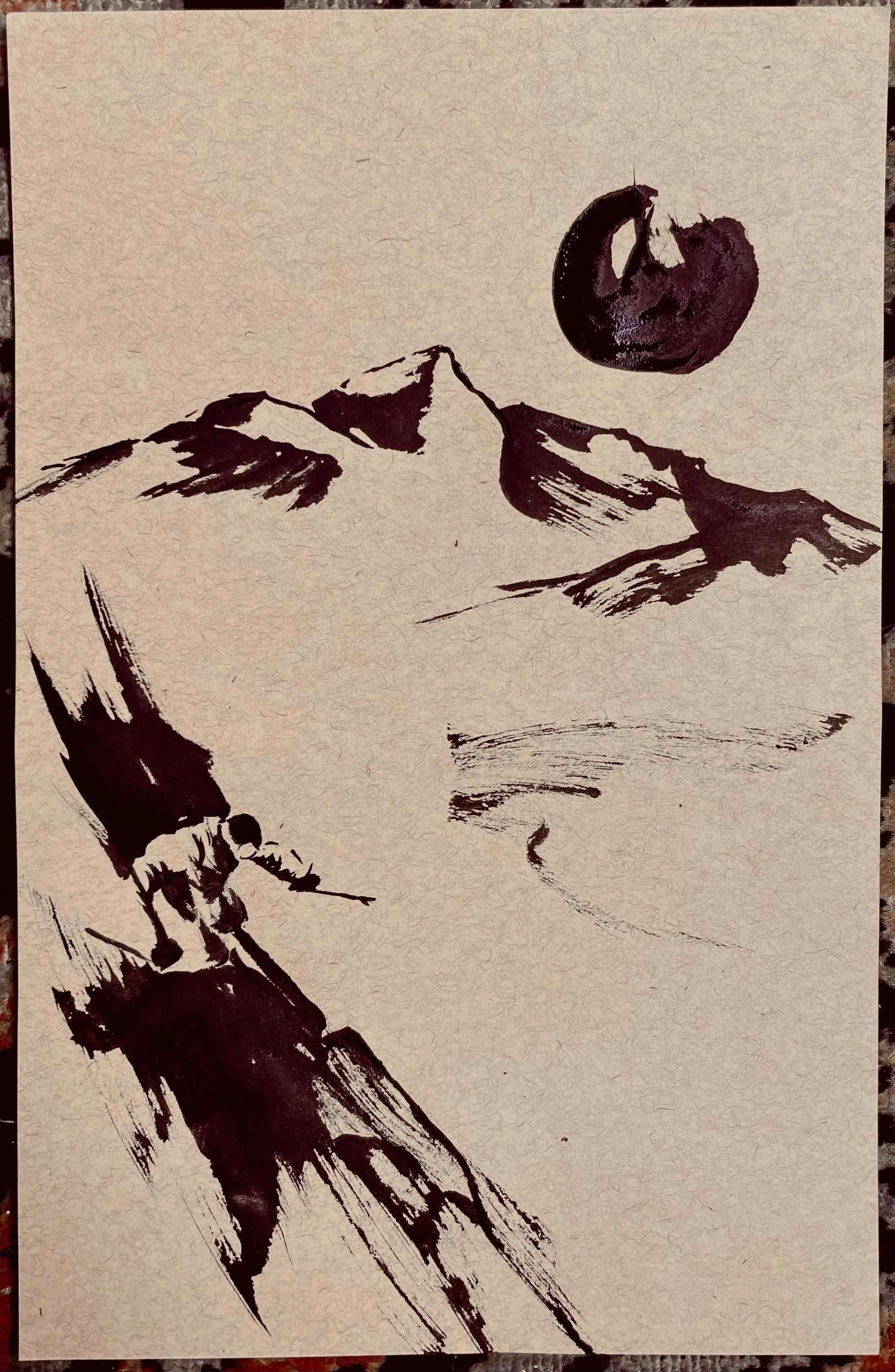 Black ink drawing of mountain peaks, with a skier descending a slope, a large moon in the sky, and a faint depiction of a face in the background.