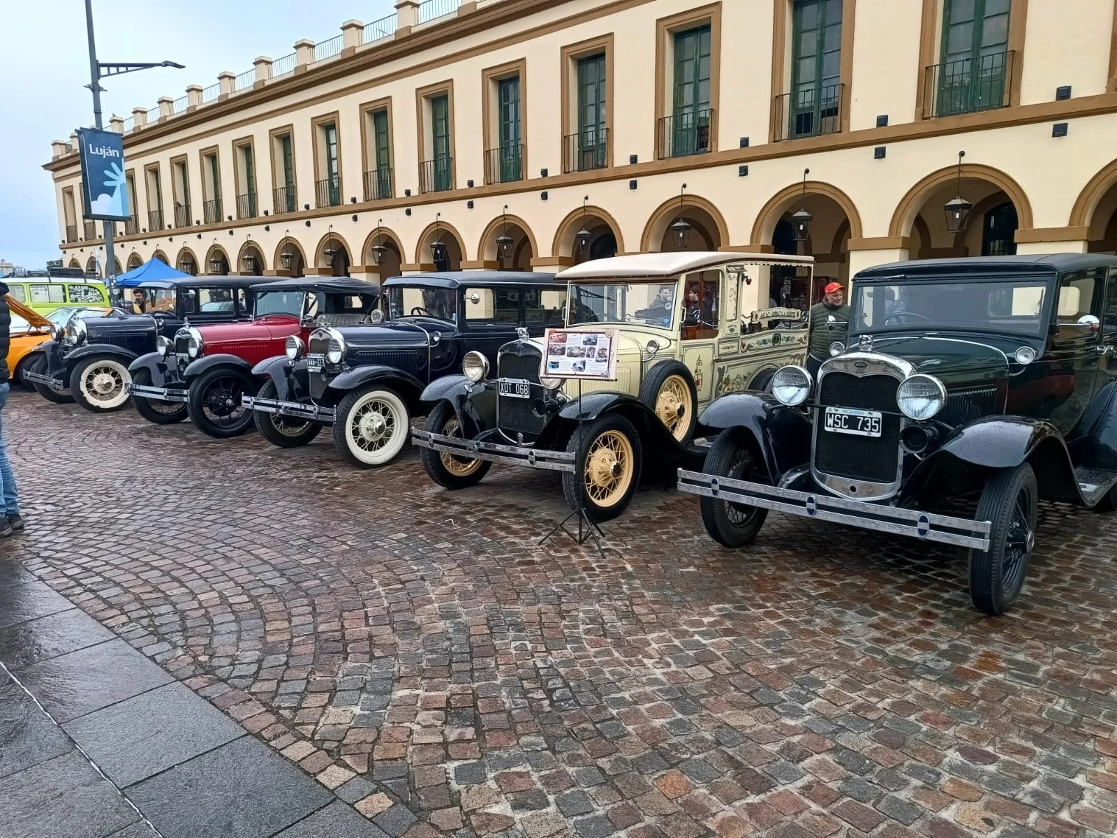 Autos antiguos en exhibición en una calle empedrada.