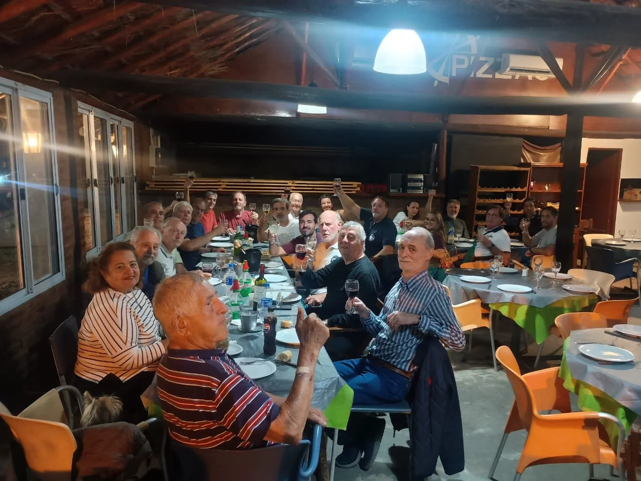 Personas en una cena en un restaurante rústico, celebrando con copas de vino y comida en la mesa