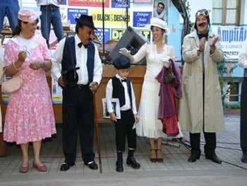 Grupo de personas vestido con ropa de época en una obra de teatro o evento cultural al aire libre.