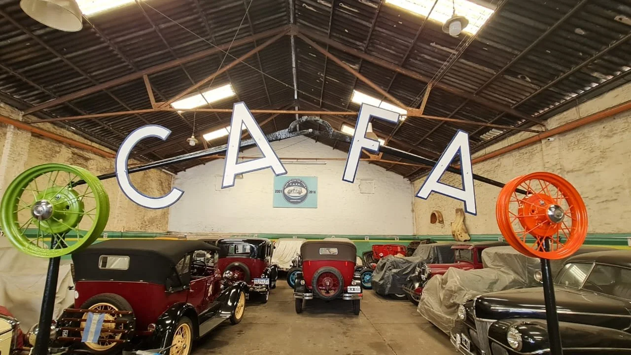 Interior de un museo de autos clásicos con varios autos antiguos y un cartel que dice 'CAFA'.