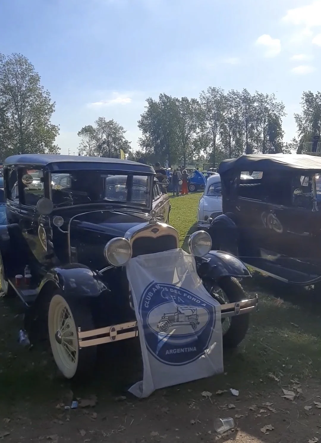 Autos antiguos en exhibición en un evento al aire libre, con un cartel que dice 'Club de Autos del Ford, Argentina'.