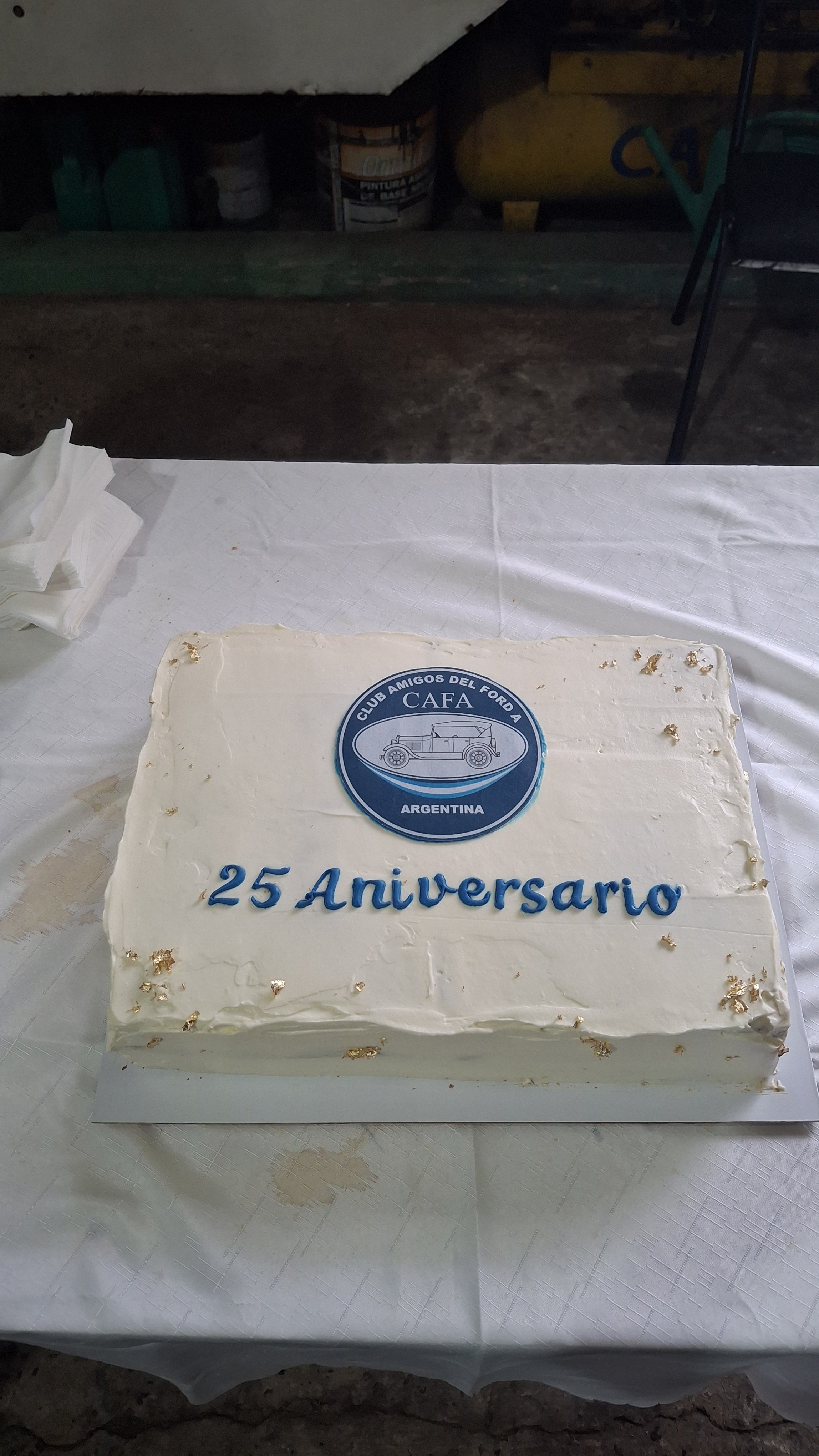 Pastel blanco con el logo del Club Amigos del Ford en Argentina y la inscripción '25 Aniversario', decorado con pequeñas hojas de oro.