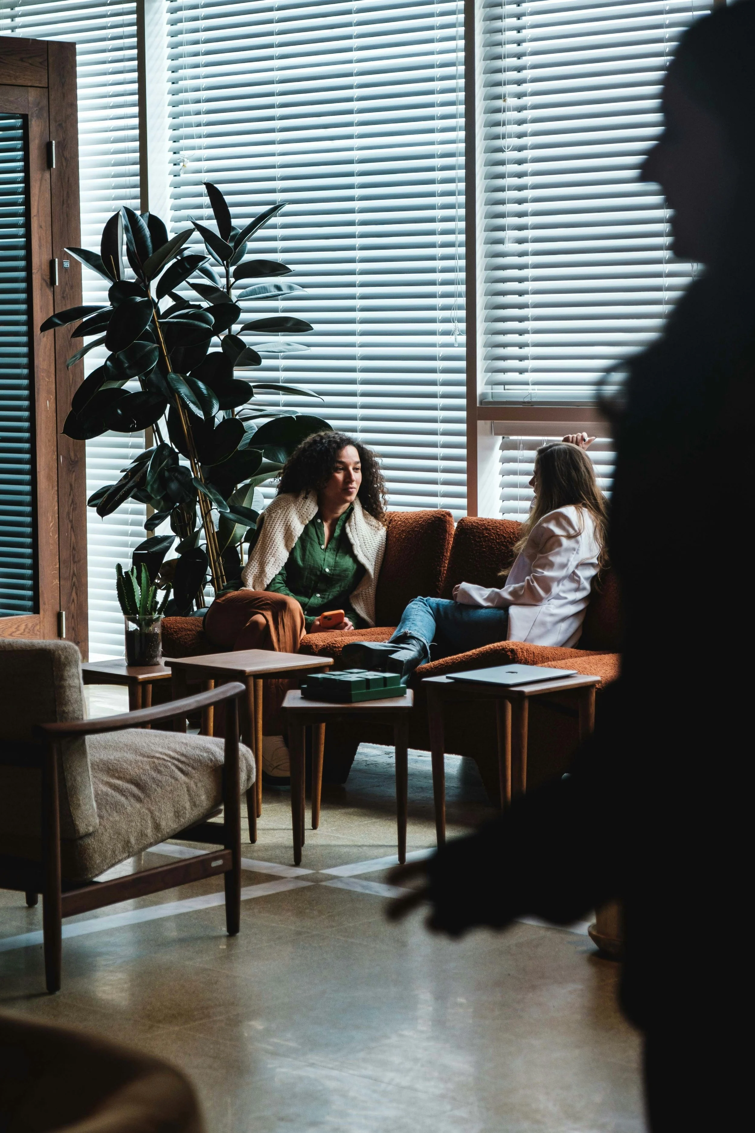 Two women sitting on a brown couch during an anxiety therapy session.