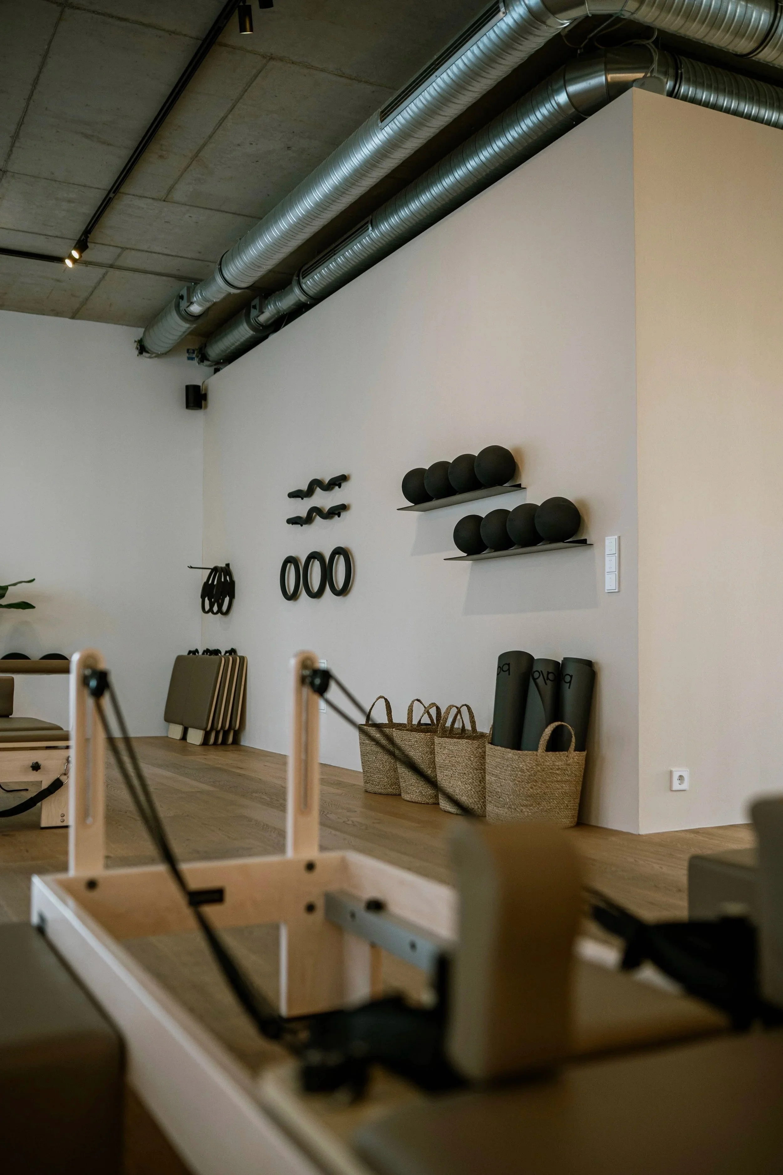 Fitnessraum mit Pilates-Geräten, Hanteln, Kettlebells, Yogamatten und Luftmatratzen in einem modernen Studio.