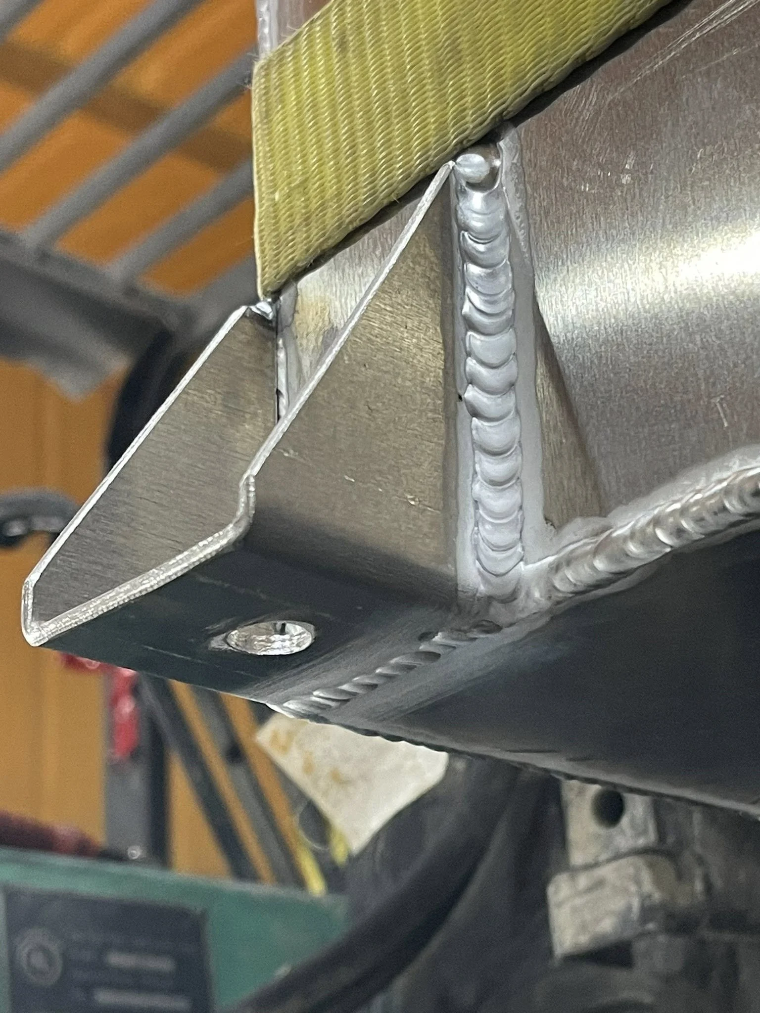 Close-up of a metallic structure with welded joints, part of industrial equipment or machinery in a workshop setting.