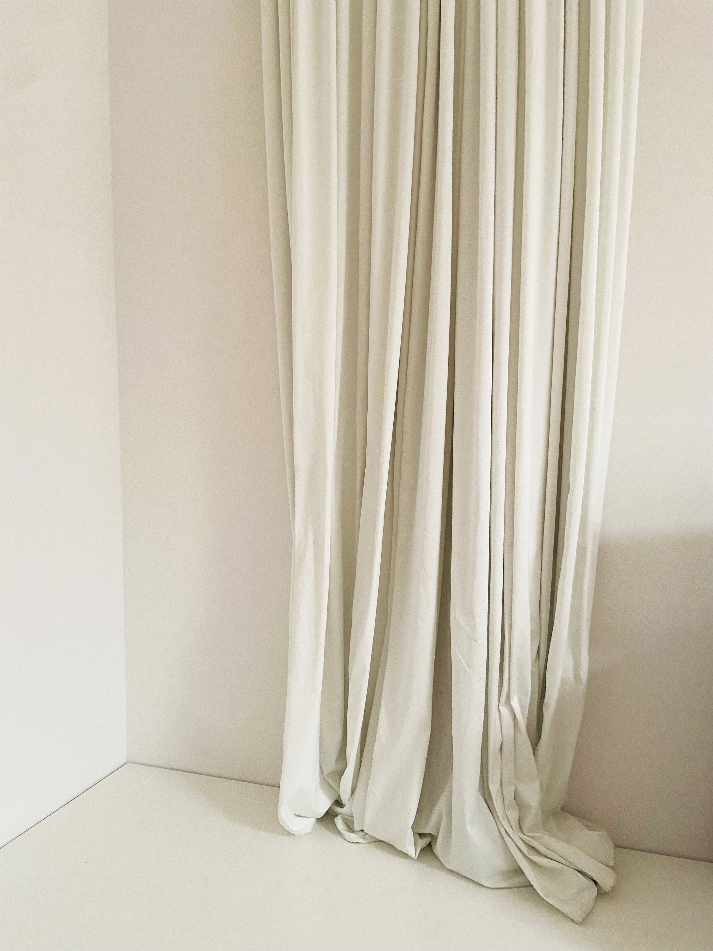 Helles, cremefarbenes Vorhang in einem Raum mit weißen Wänden.