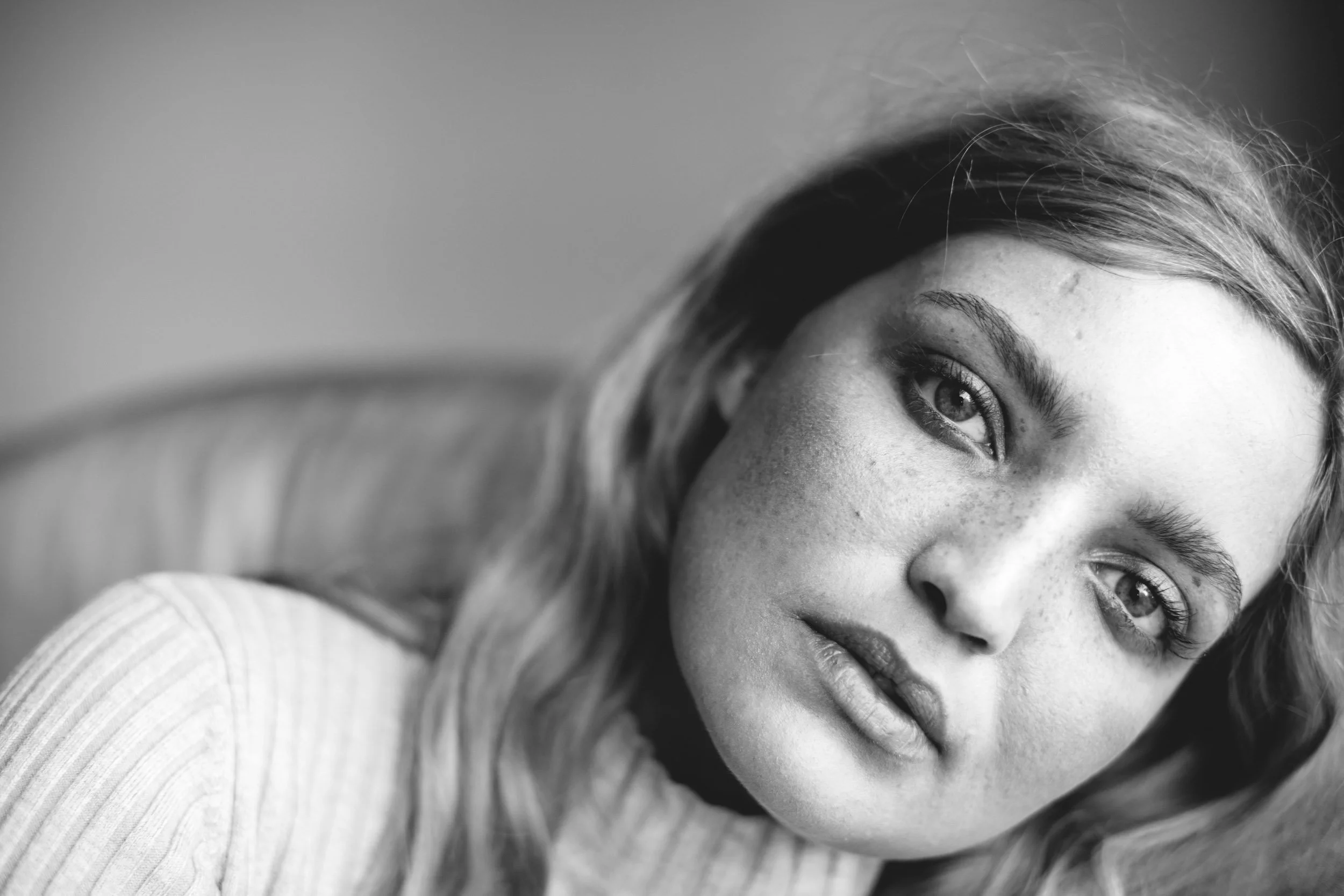 Schwarz-weiß-Fotografie eines jungen Mädchens mit langen Haaren, die direkt in die Kamera schaut.