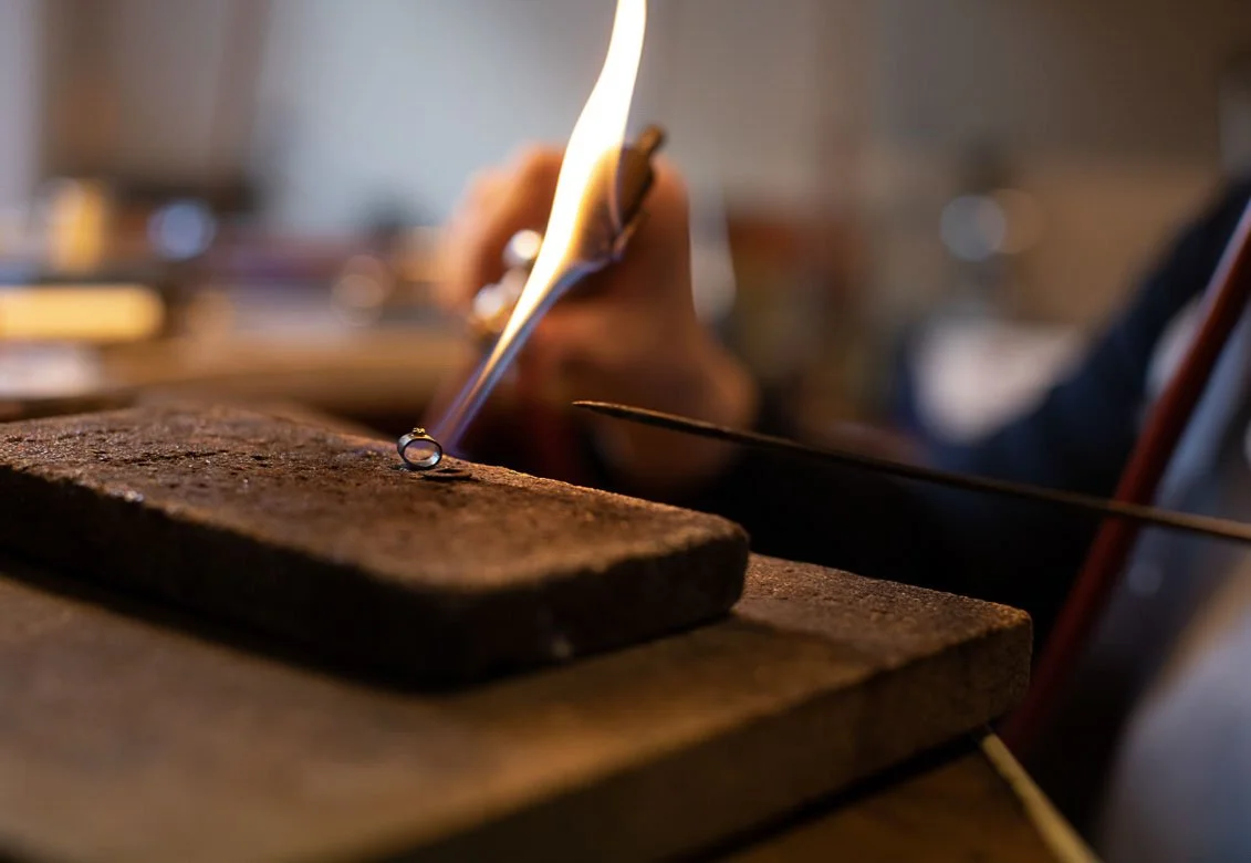 Jemand schmiedet Metall mit Feuer, Funken und Zange.