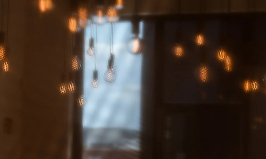 Blick durch ein Fenster mit verrückter Kulisse, Lichterketten und Baum im Hintergrund.