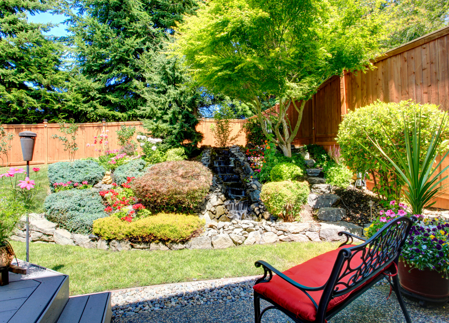 Backyard landscape design highlighting a lush garden bed, stone walkway, and bench