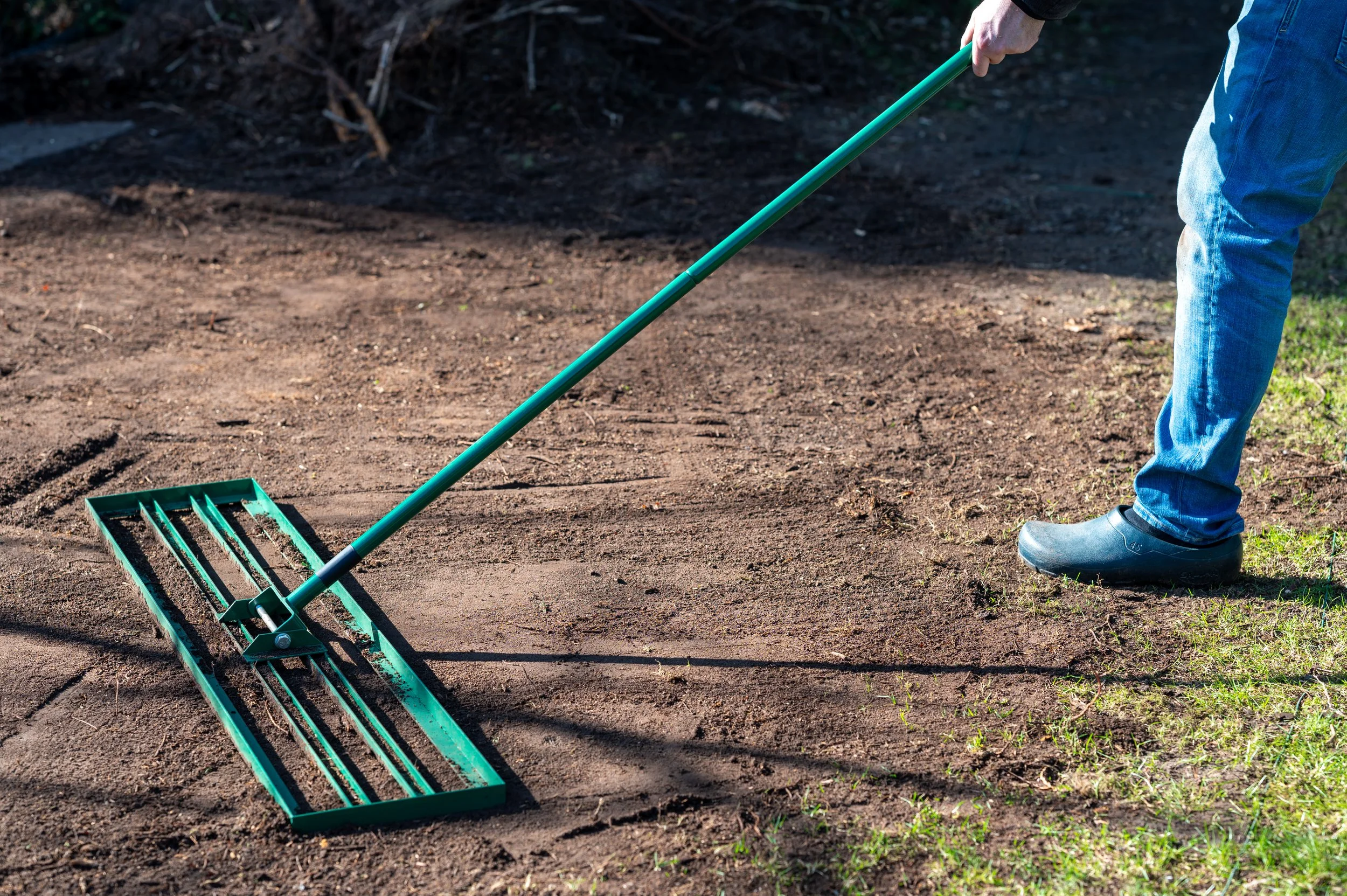 Technician Smoothing out lawn to prevent pooling and proper drainage