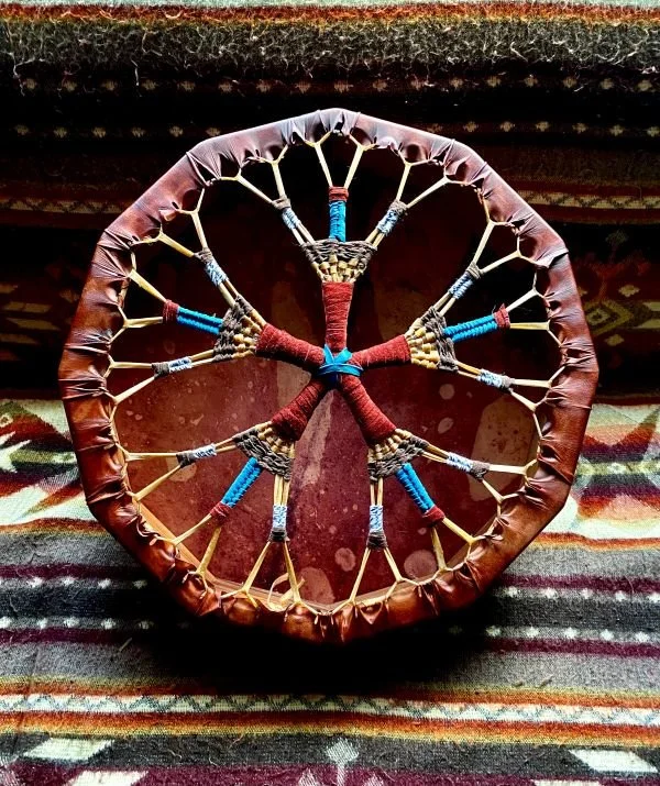 Traditional Native American dreamcatcher with a circular frame, woven web, and colorful yarn accents, placed on a patterned fabric surface.