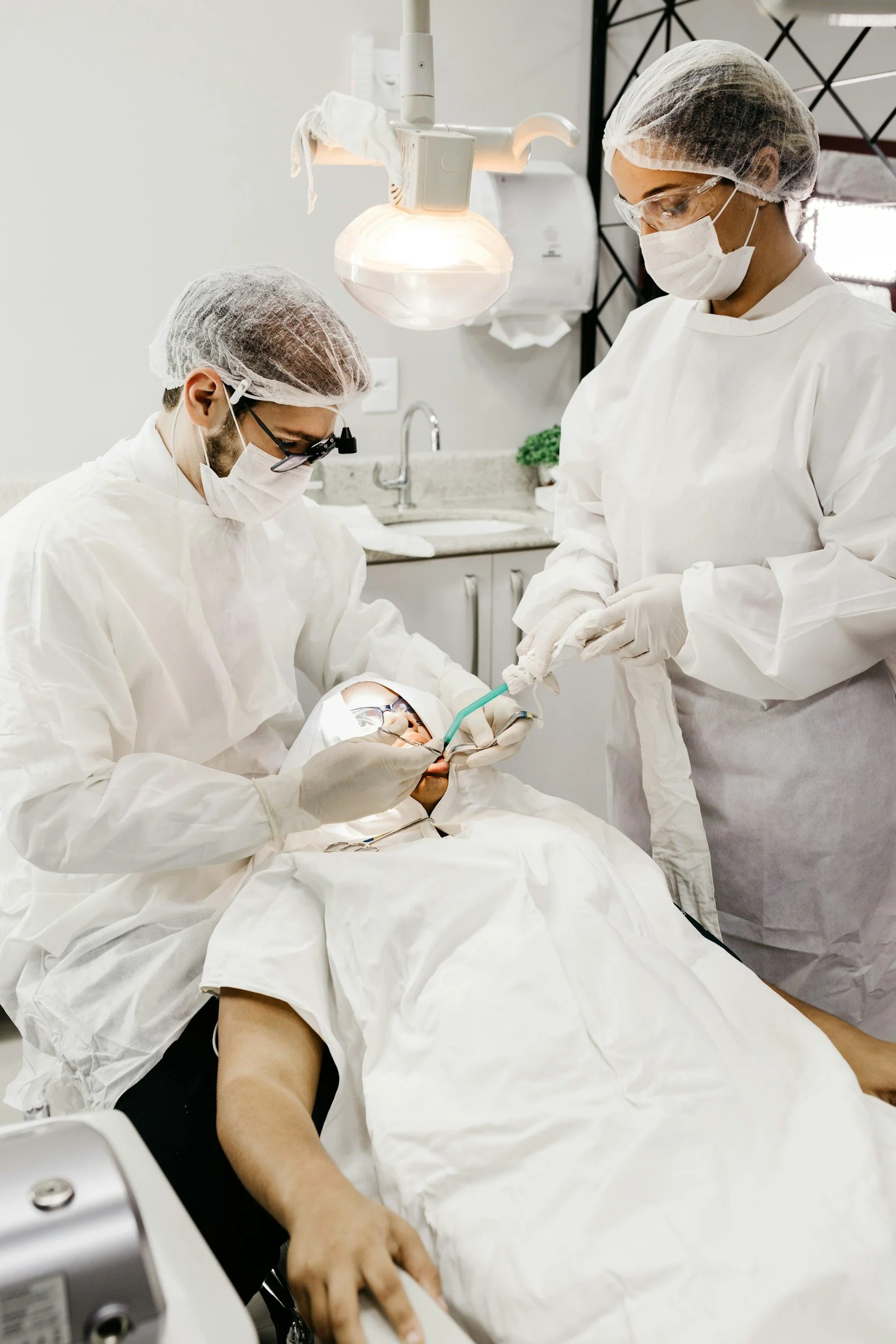 Dental team in surgical gowns treating a patient under anesthesia