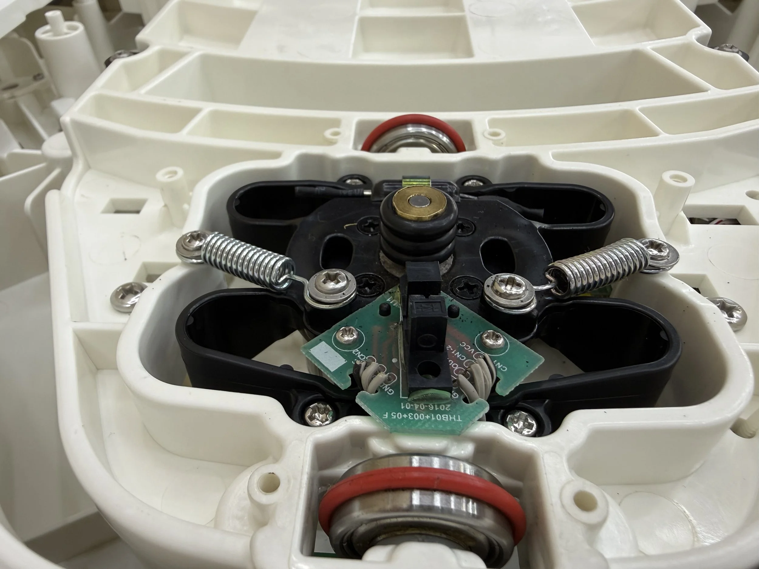 Internal view of a SNOO motor showing metal springs, wiring, and a working area with a white plastic casing.