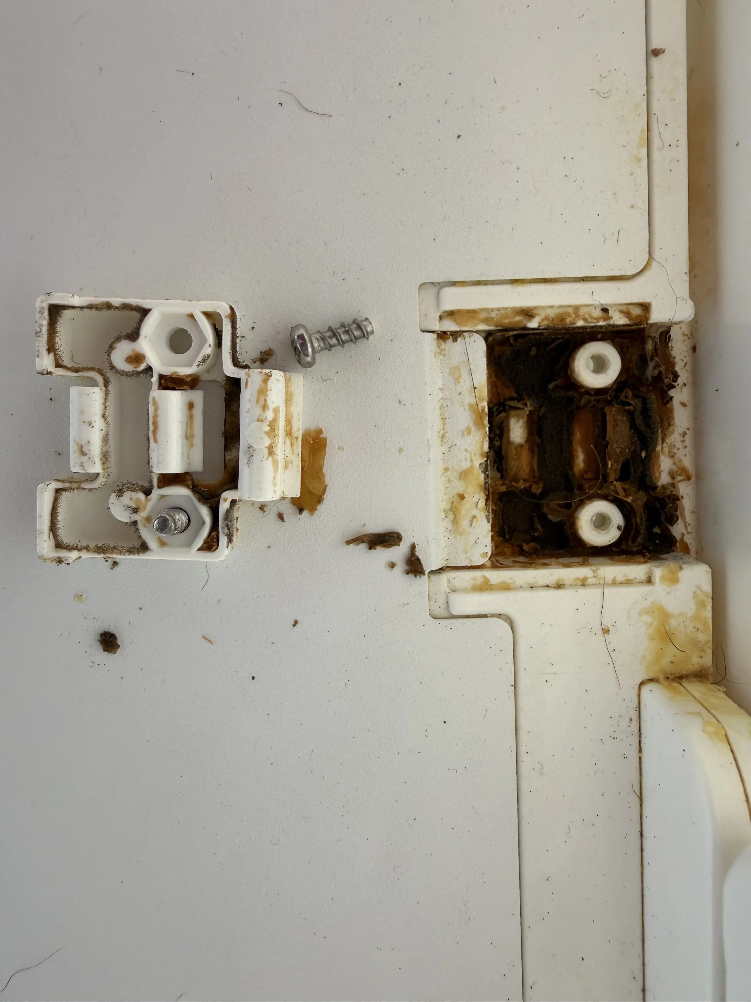 A damaged and dirty white plastic SNOO bracket visible spit up, grime, and missing parts, lying on a white surface.