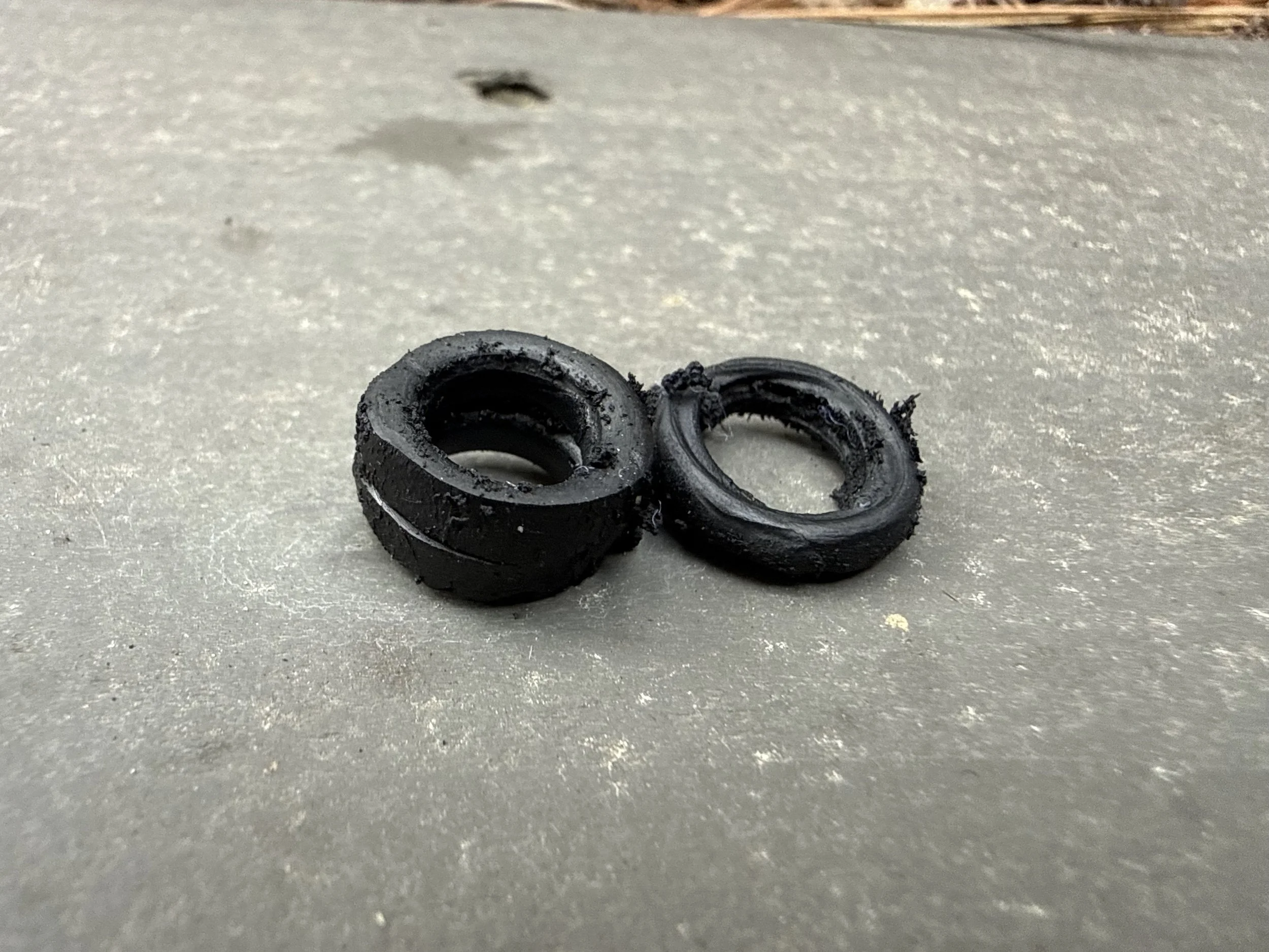 Two small, black rubber SNOO o-rings on a flat, light-colored surface.