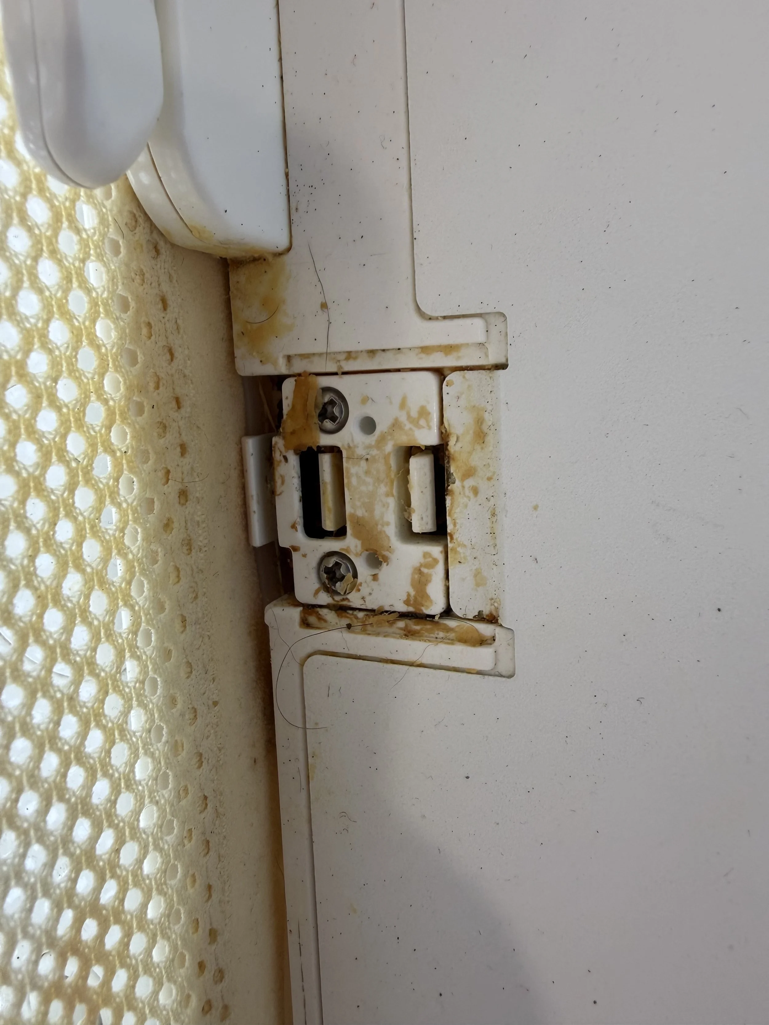 Close-up of a dirty, damaged SNOO plastic bracket with caked spit up and grime.